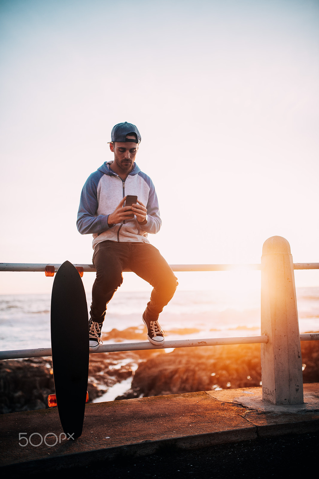 Canon EOS 5DS sample photo. Young adult man sitting on railing at ocean browsing with smart photography