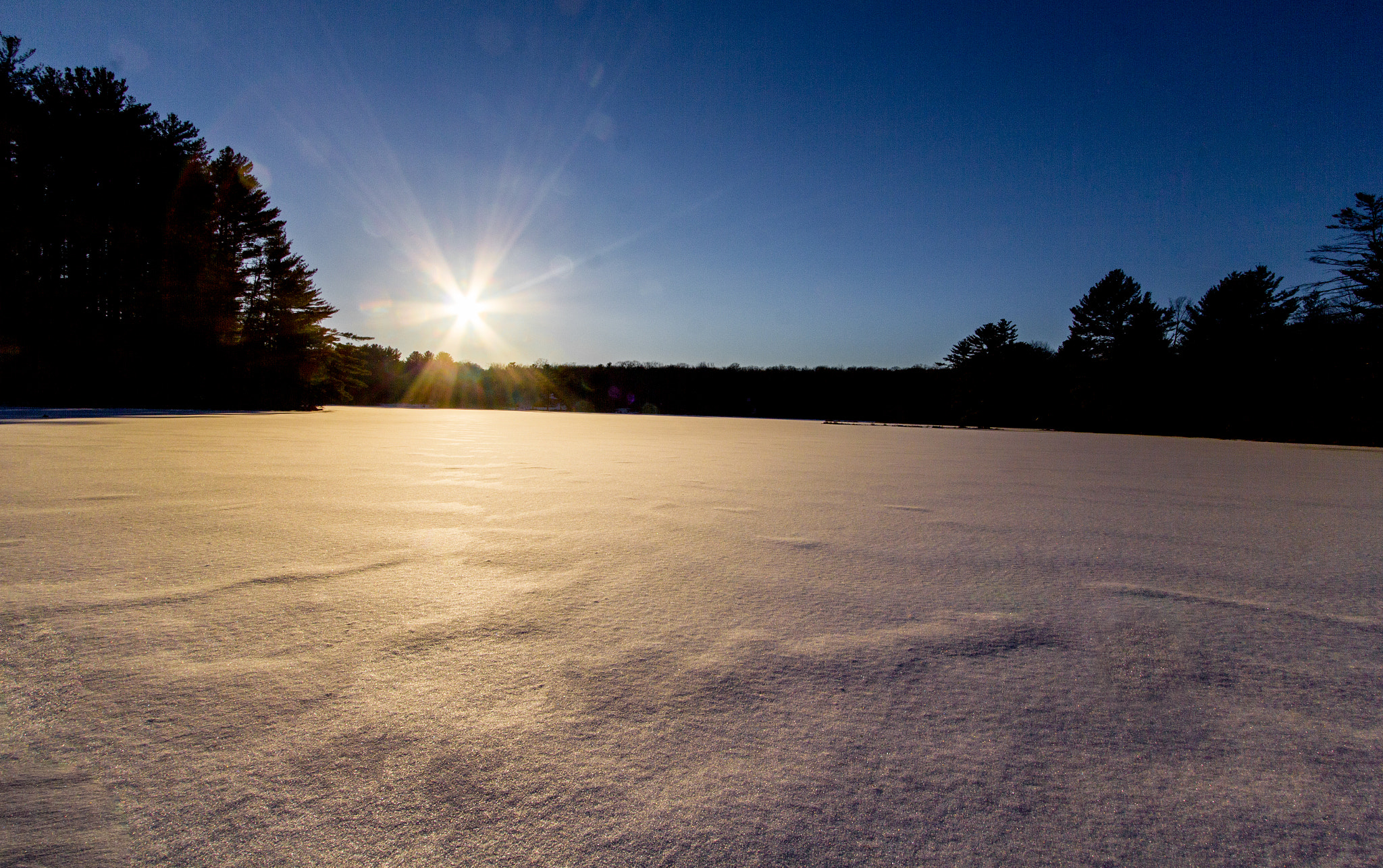 Canon EOS 550D (EOS Rebel T2i / EOS Kiss X4) + Canon EF-S 10-22mm F3.5-4.5 USM sample photo. Sunflare over a frozen lake photography