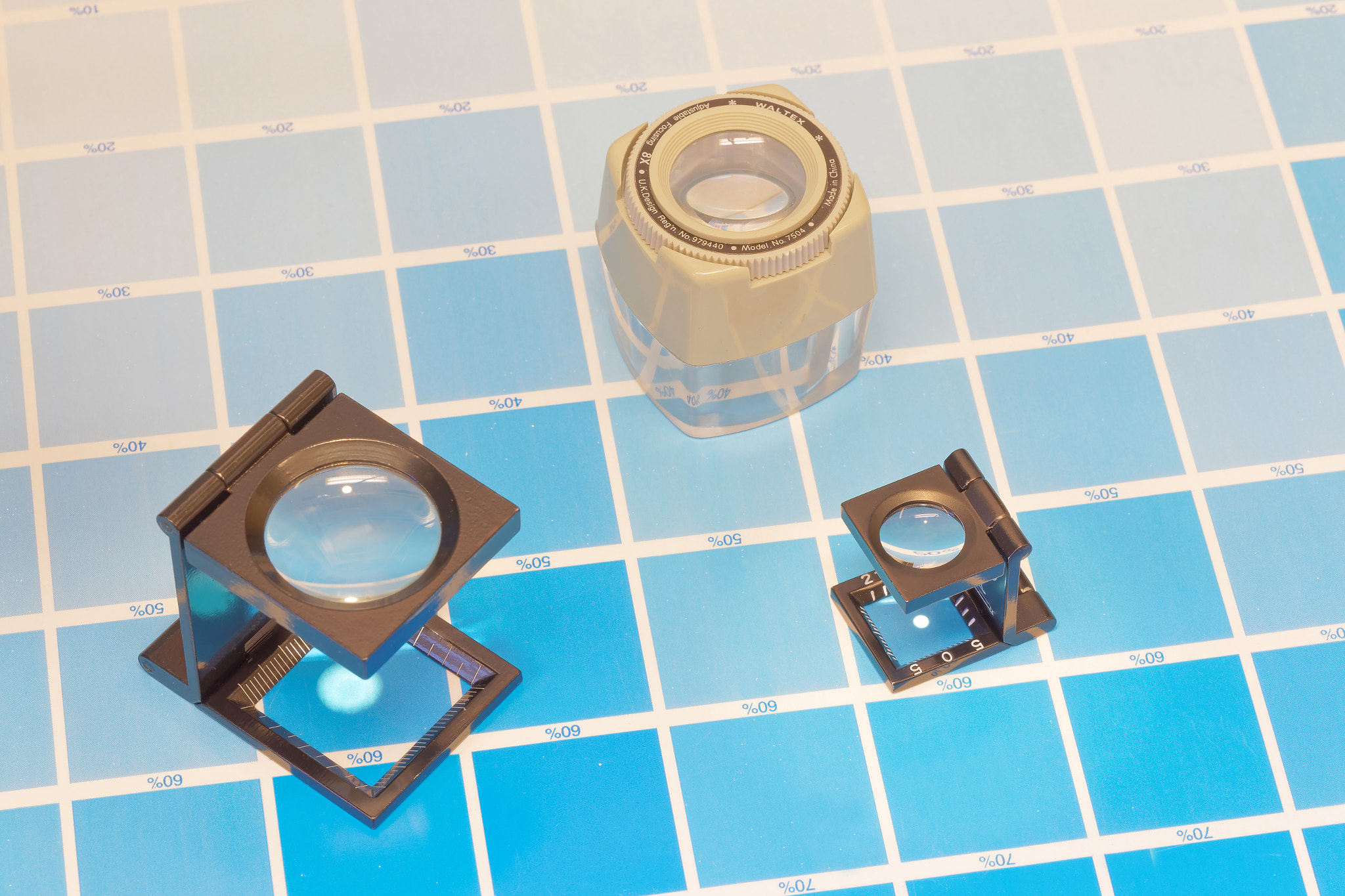 Canon EF 100mm F2.8 Macro USM sample photo. Three magnifier or printer's loupe sits on a cyan test sheet photography