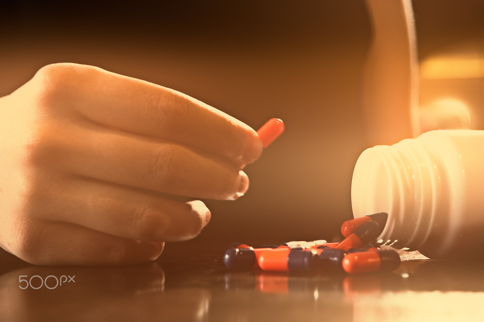 Samsung NX500 sample photo. White bottle pouring pills on polished wooden table and a female's hand holding one pill in... photography