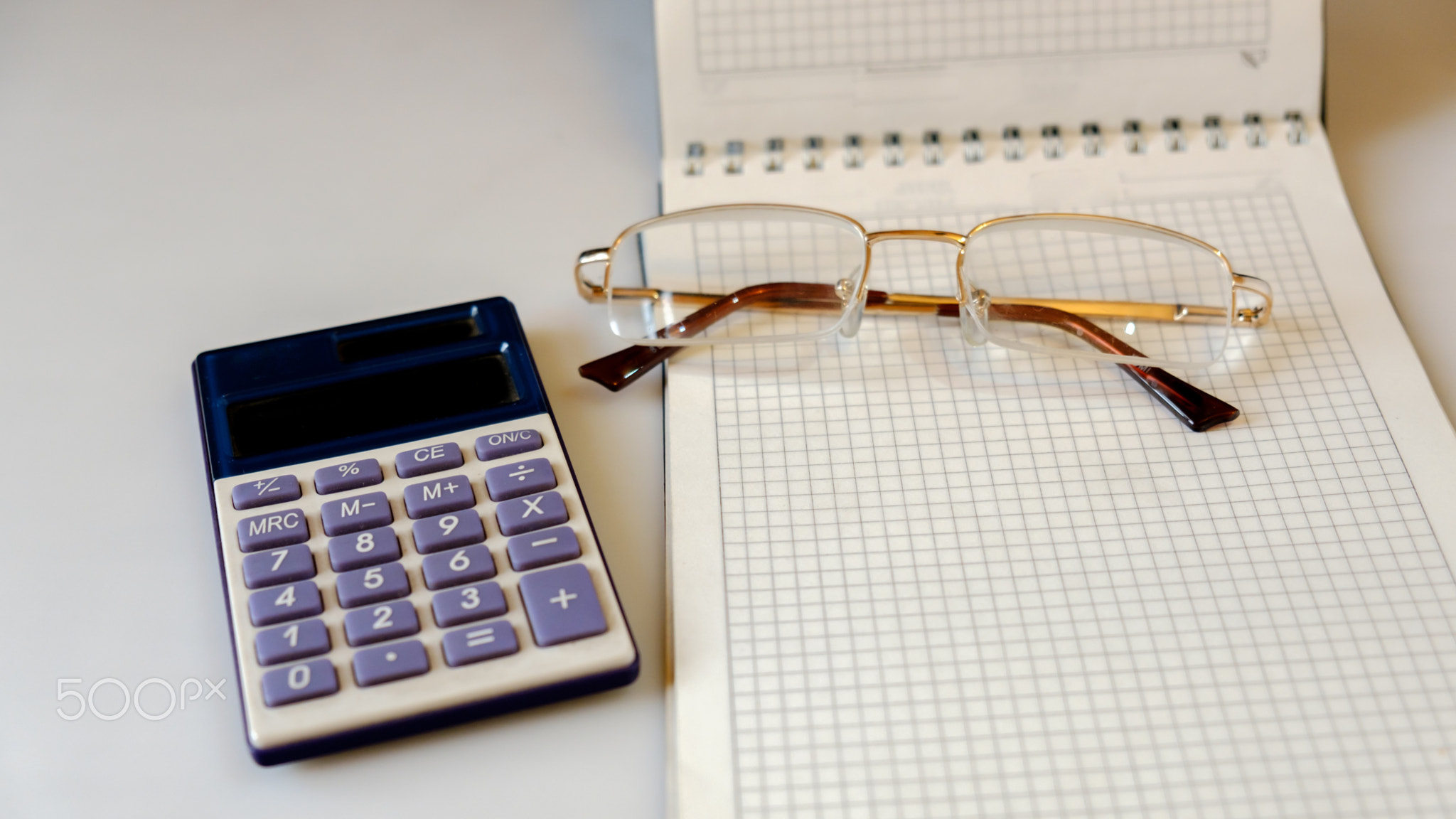 notebook with glasses and calculator on a light background