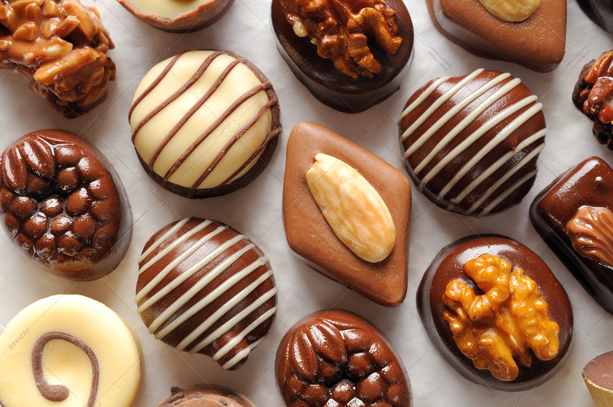 Tamron SP 24-70mm F2.8 Di VC USD sample photo. Assorted aligned bonbons on a white textured paper top view photography