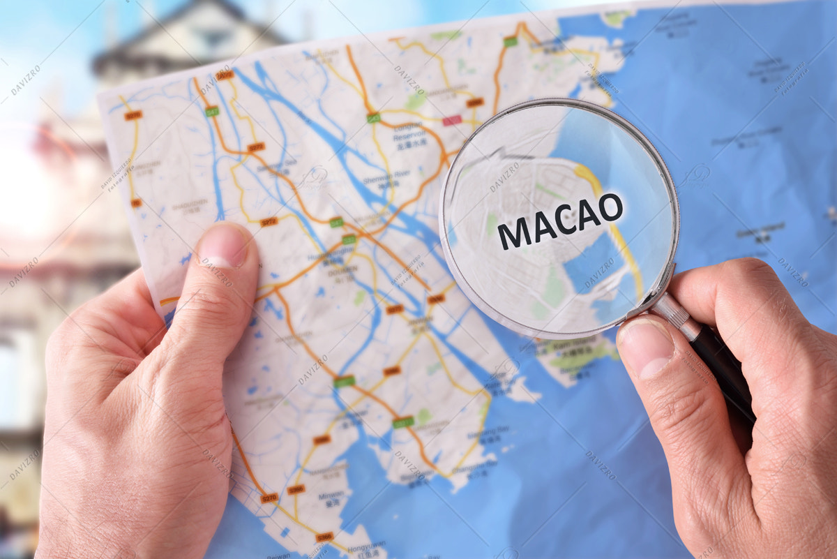 Man consulting a map of Macao with a magnifying glass