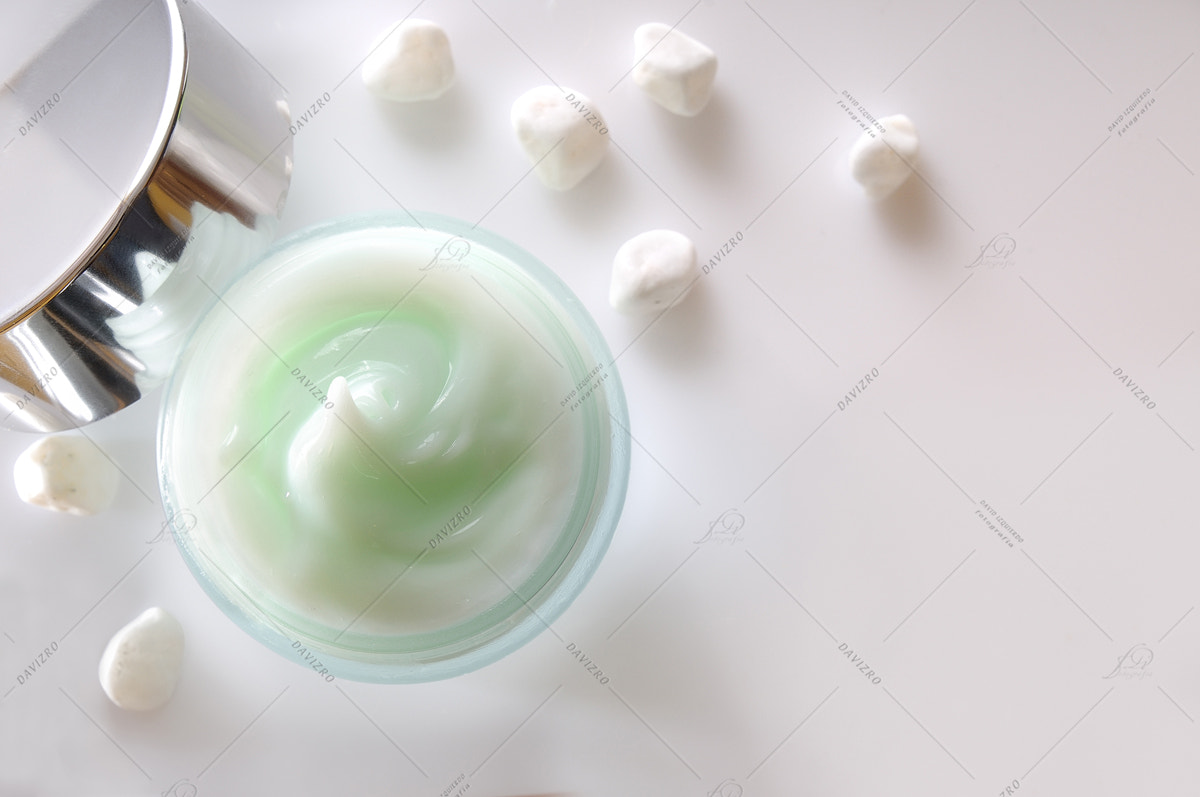 Cream jar open and small white stones isolated top view