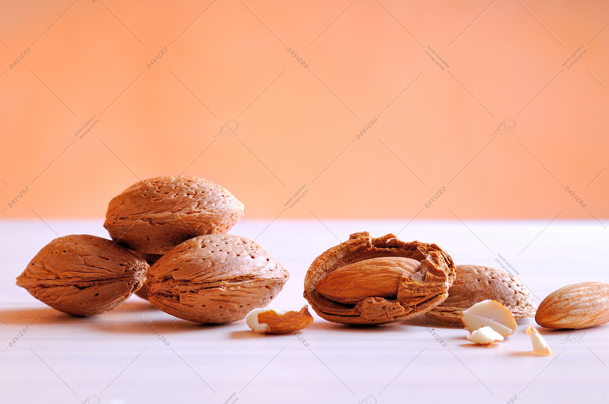 Nikon D300 sample photo. Almonds on a white table and orange background photography