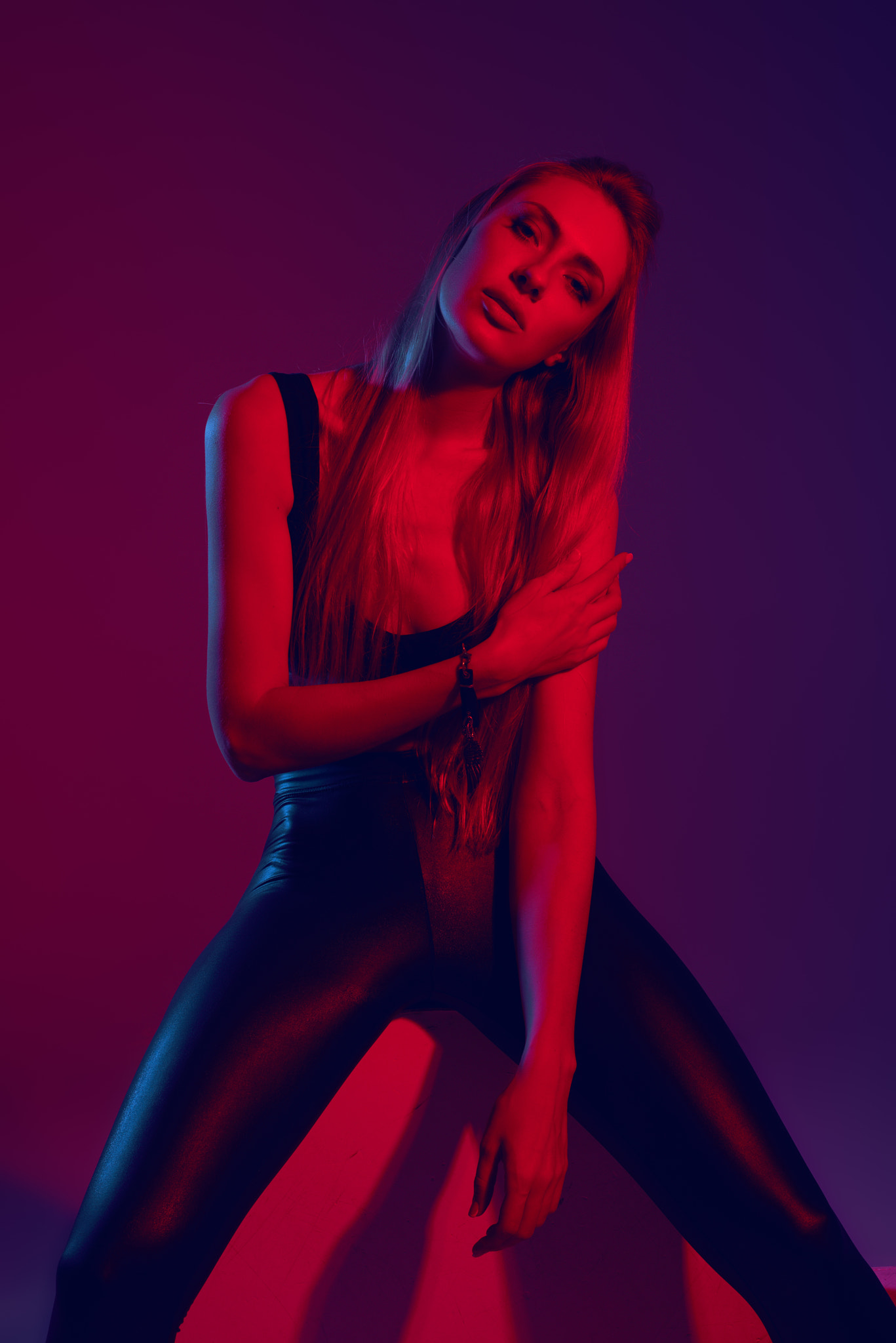 Fashion portrait of young girl in the studio with color filters in black leather pants. fashion...