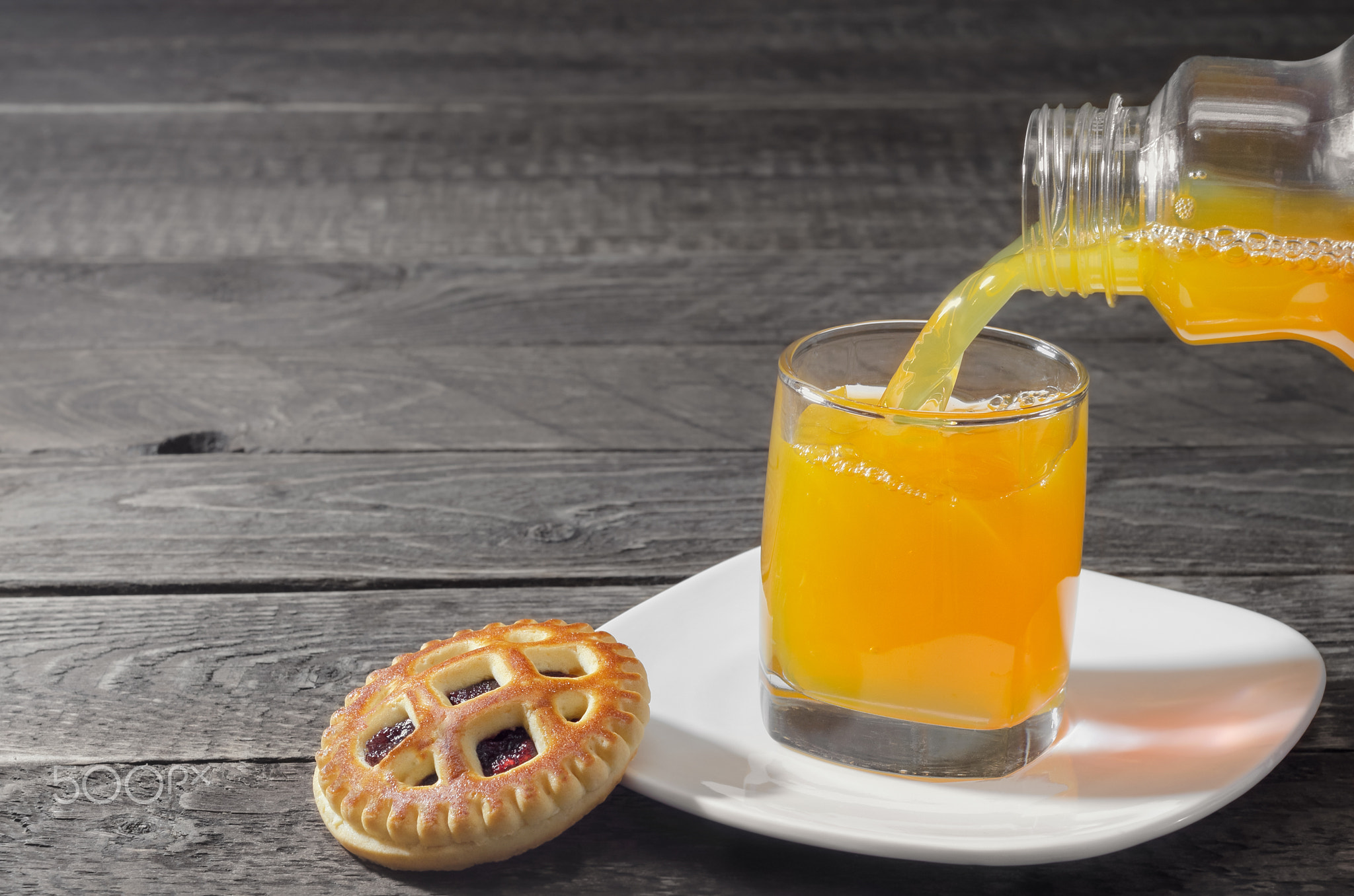 Cookies and juice is poured into a glass on gray background wood. Selective focus.