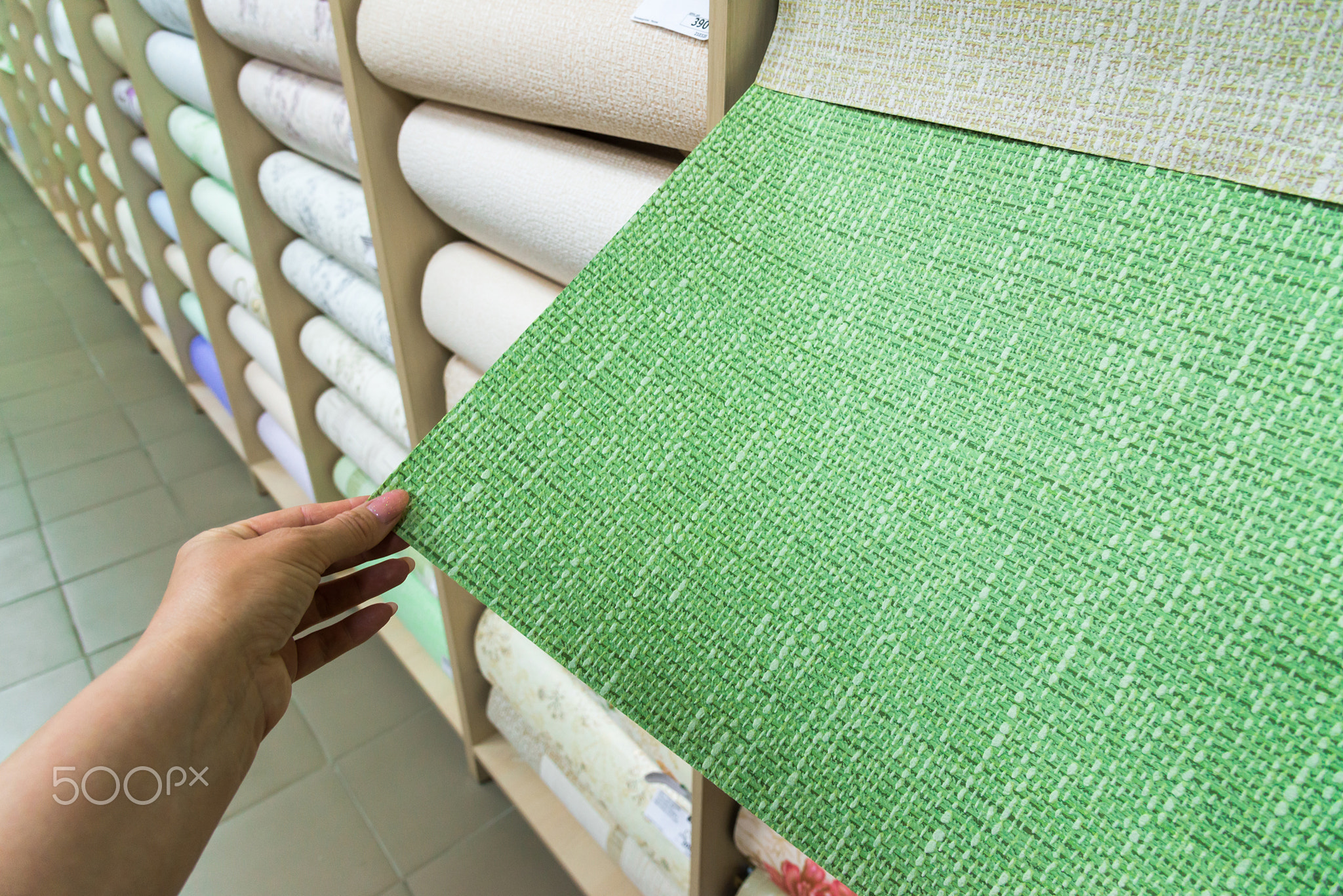 female hand holding green wallpaper in store