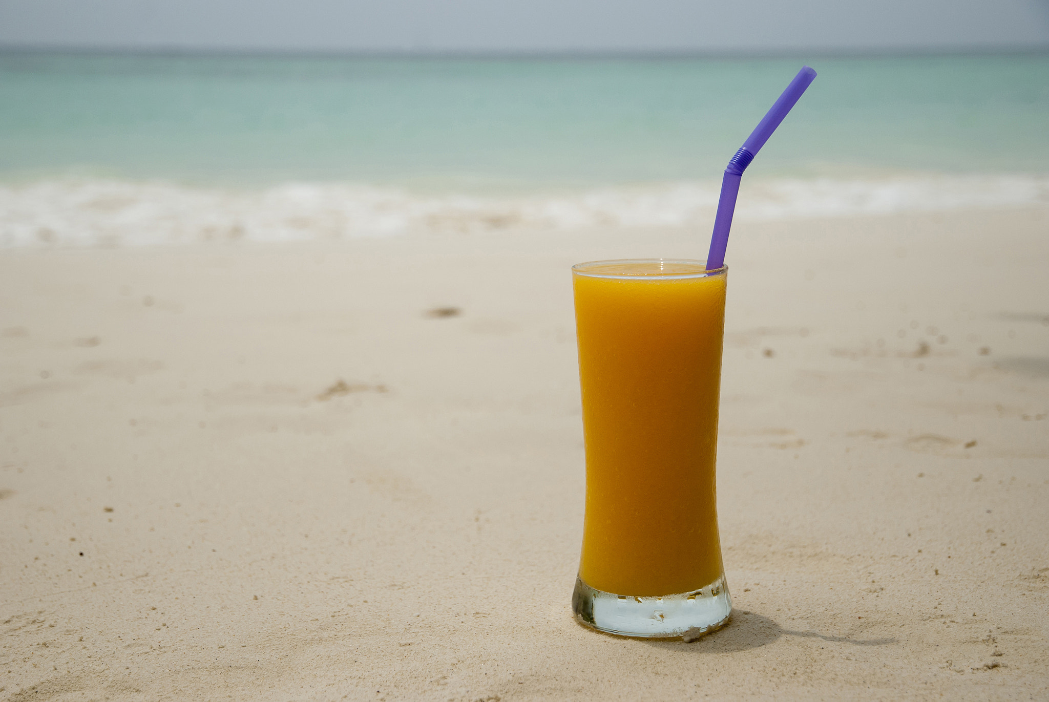 Nikon D80 + Nikon AF-S DX Nikkor 16-85mm F3.5-5.6G ED VR sample photo. Glass with juice on the tropical beach with a sea and sand as a photography