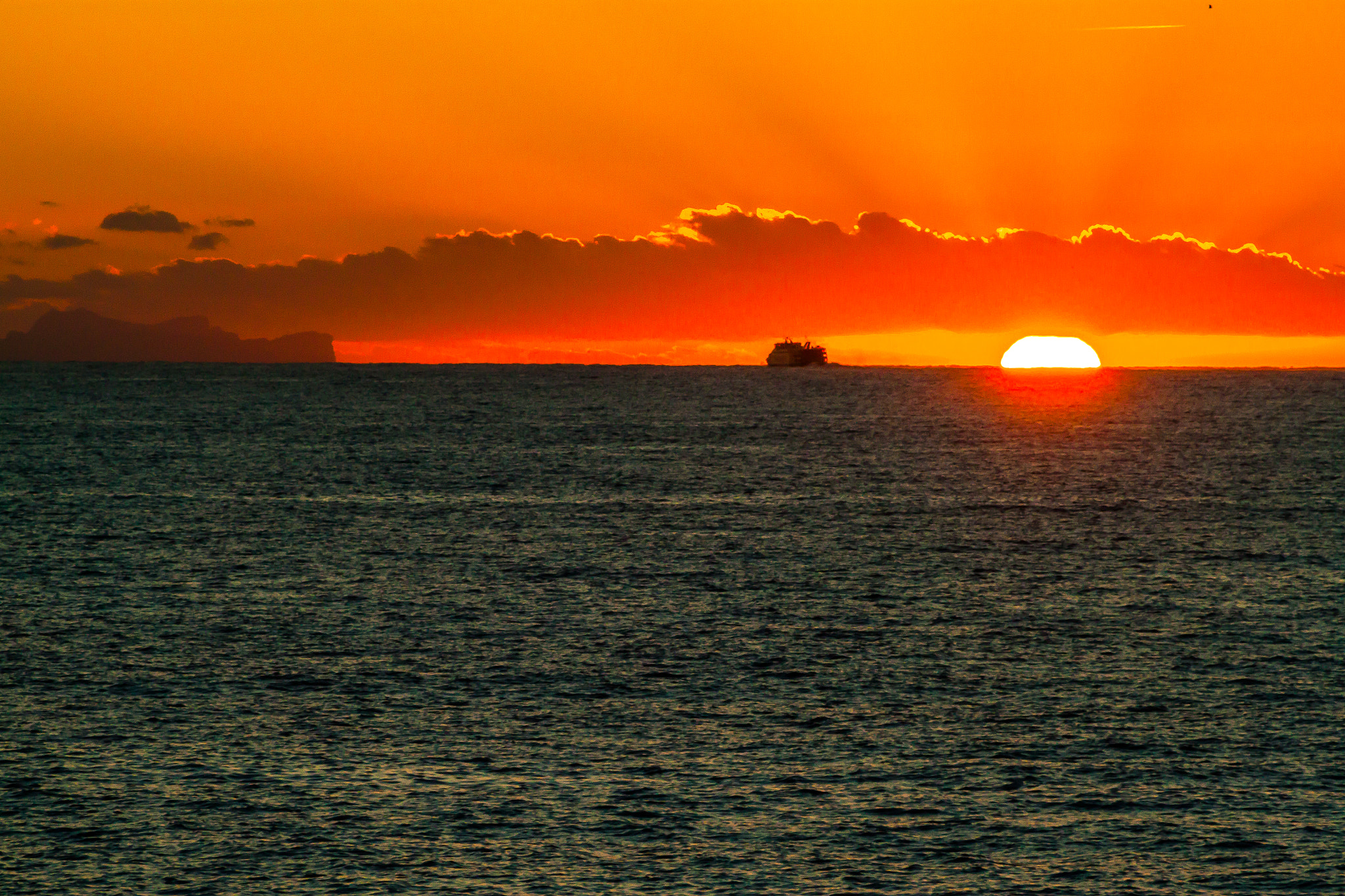 Canon EOS 500D (EOS Rebel T1i / EOS Kiss X3) sample photo. Sun setting below cloud as ferry heads away photography