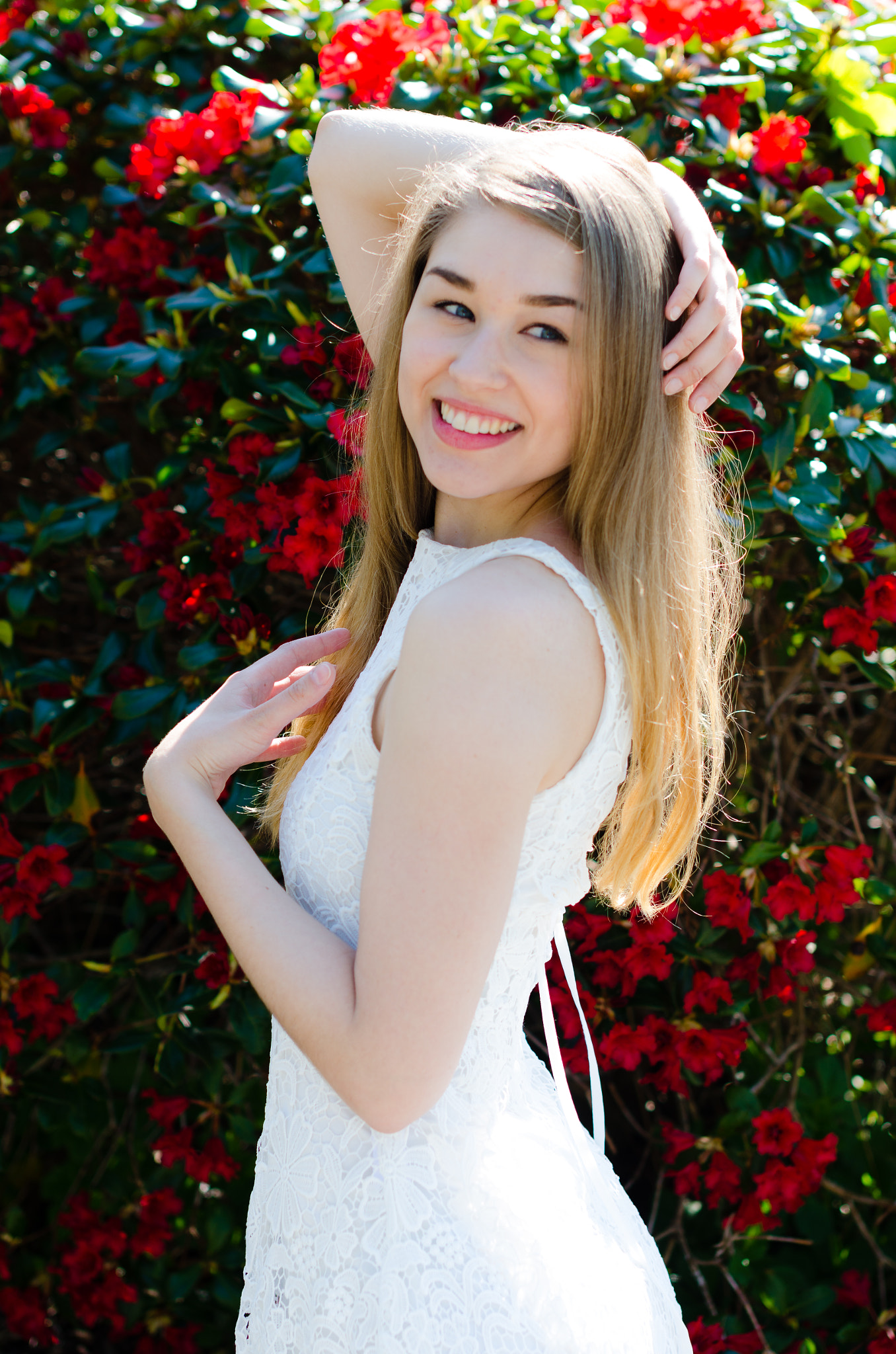 Nikon D7000 sample photo. Beautiful female model in front of red flower bush photography