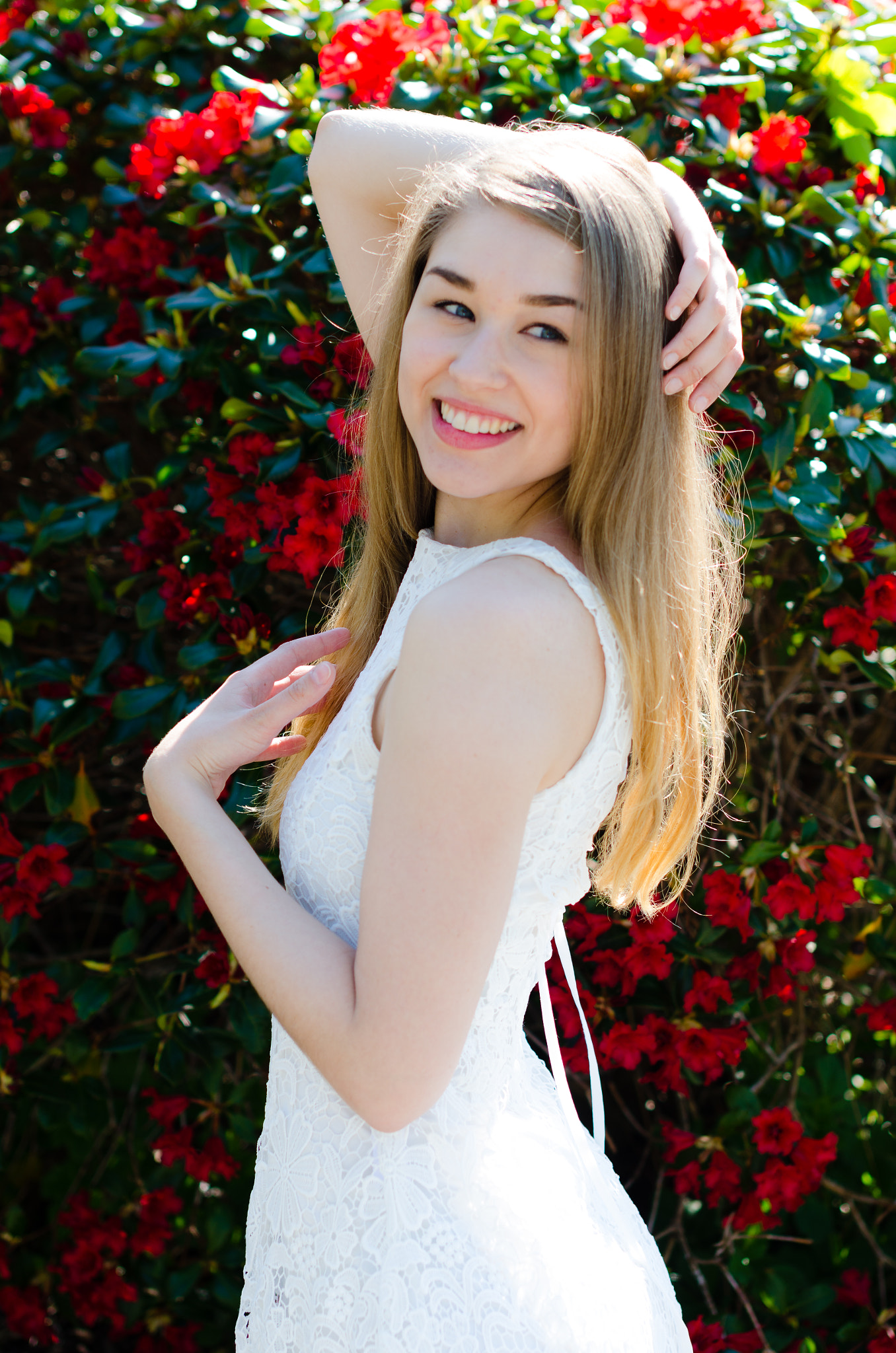 Nikon D7000 + Sigma 50mm F1.4 EX DG HSM sample photo. Beautiful female model in front of red flower bush photography