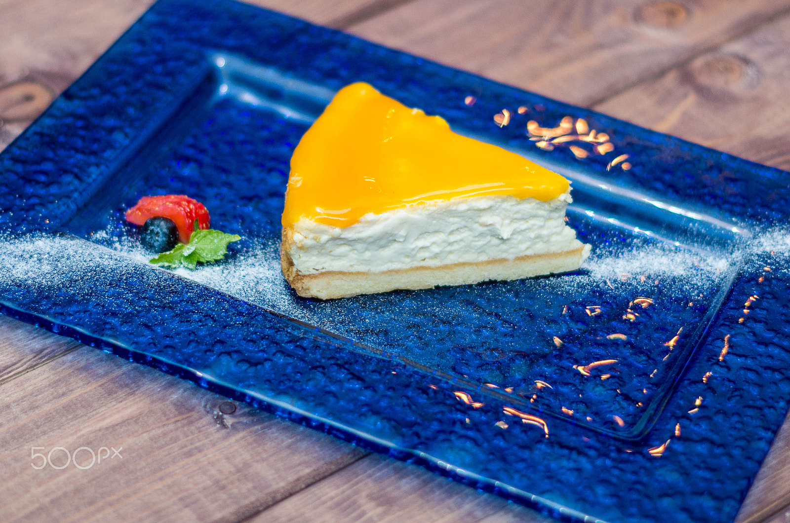Pentax K-5 II sample photo. Cheesecake with mango sauce, passion fruit on a blue background photography