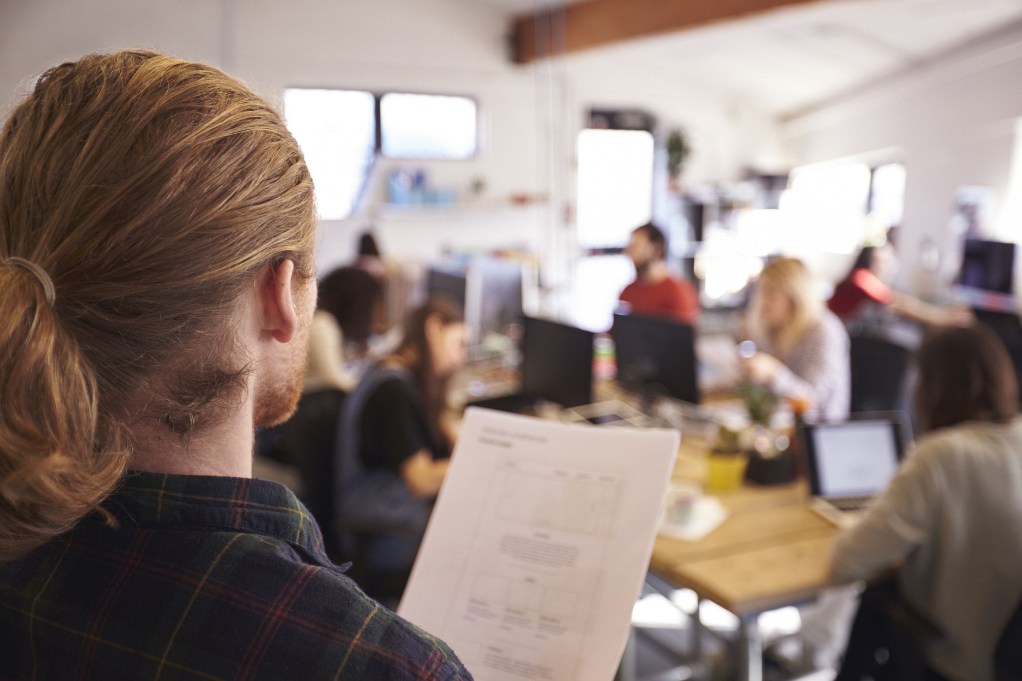 Designer Looking At Document In Busy Office