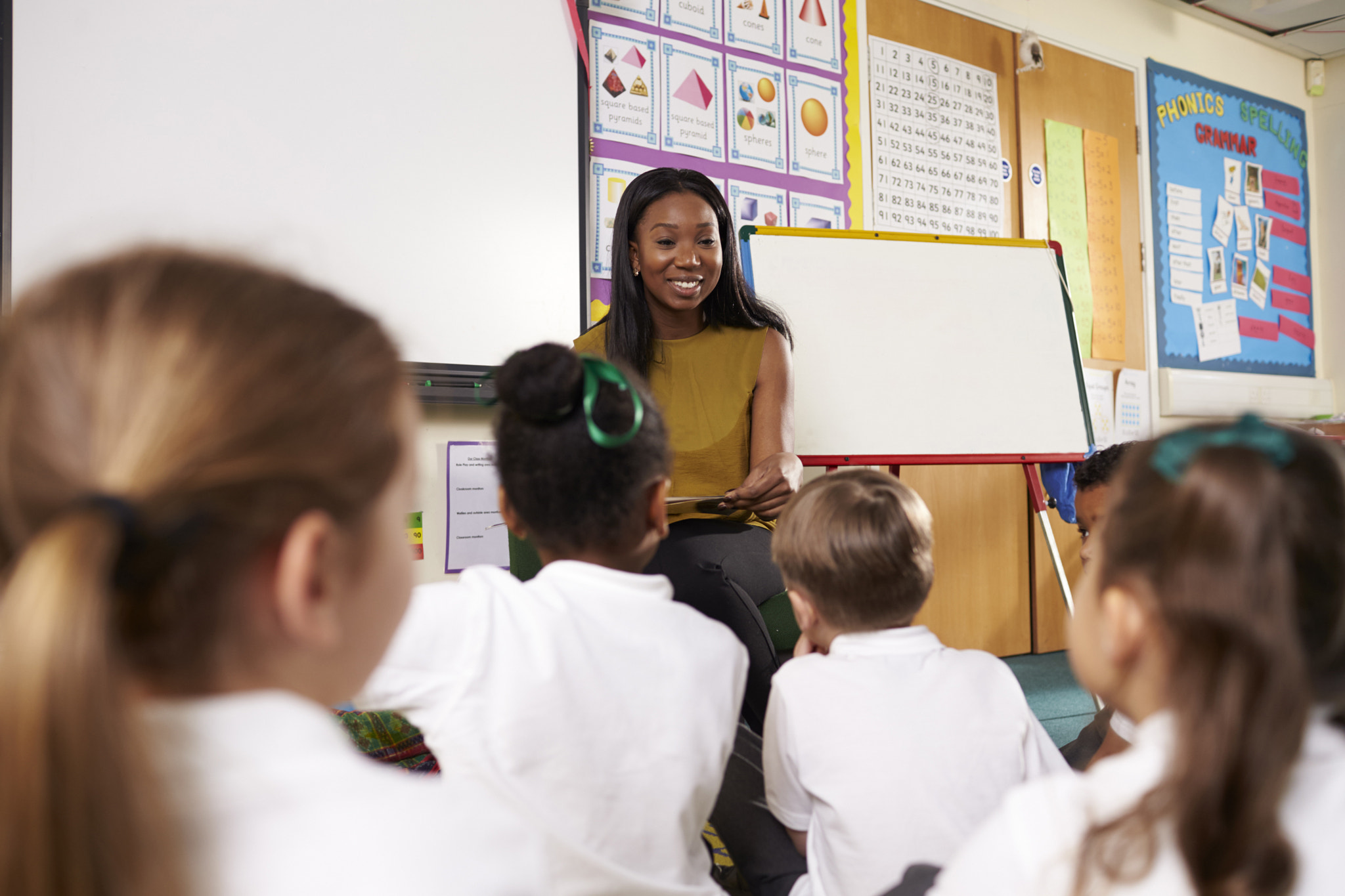 Teacher Reading To Elementary School Pupils In Classroom