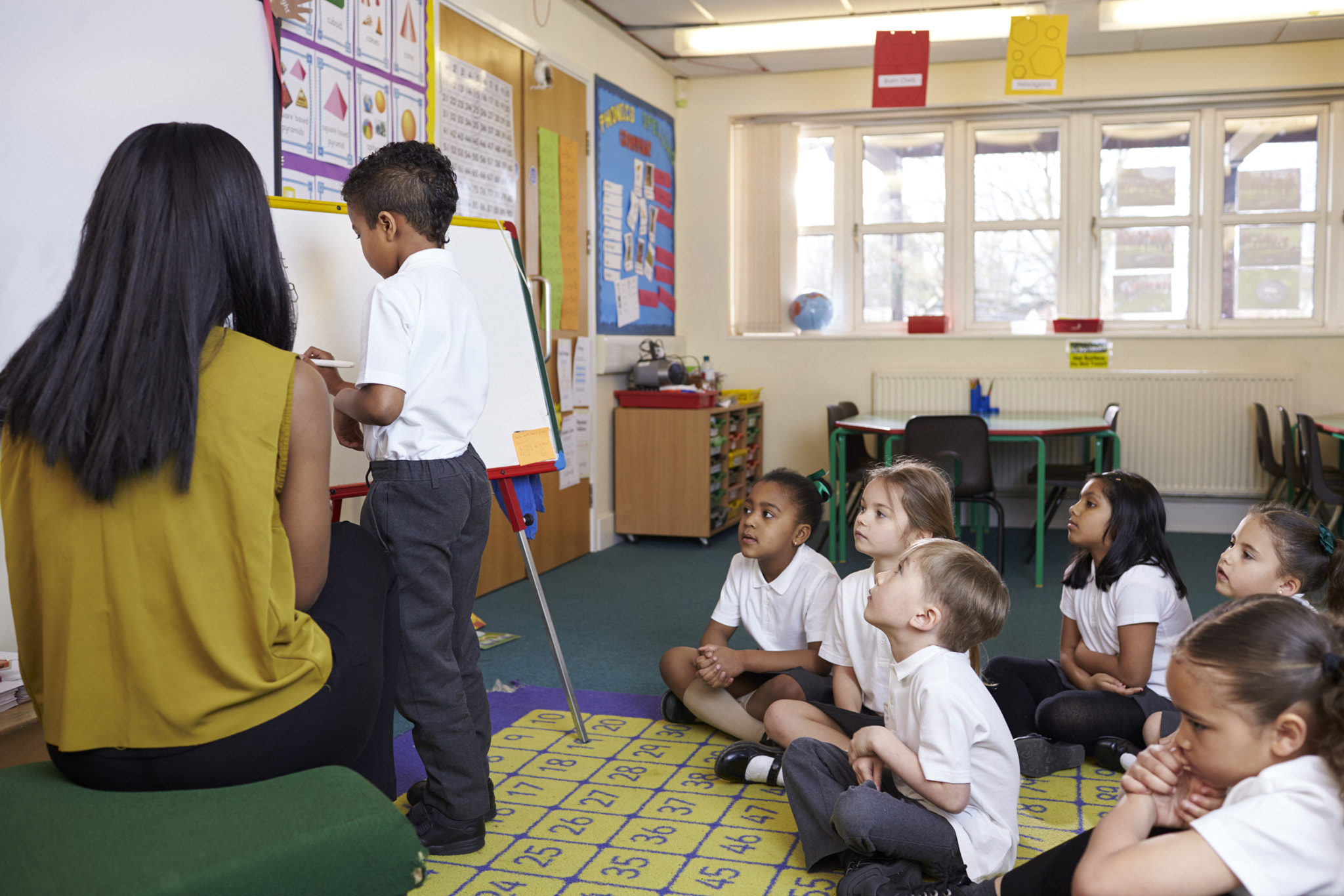 Elementary School Pupil Writing On Whiteboard In Classroom