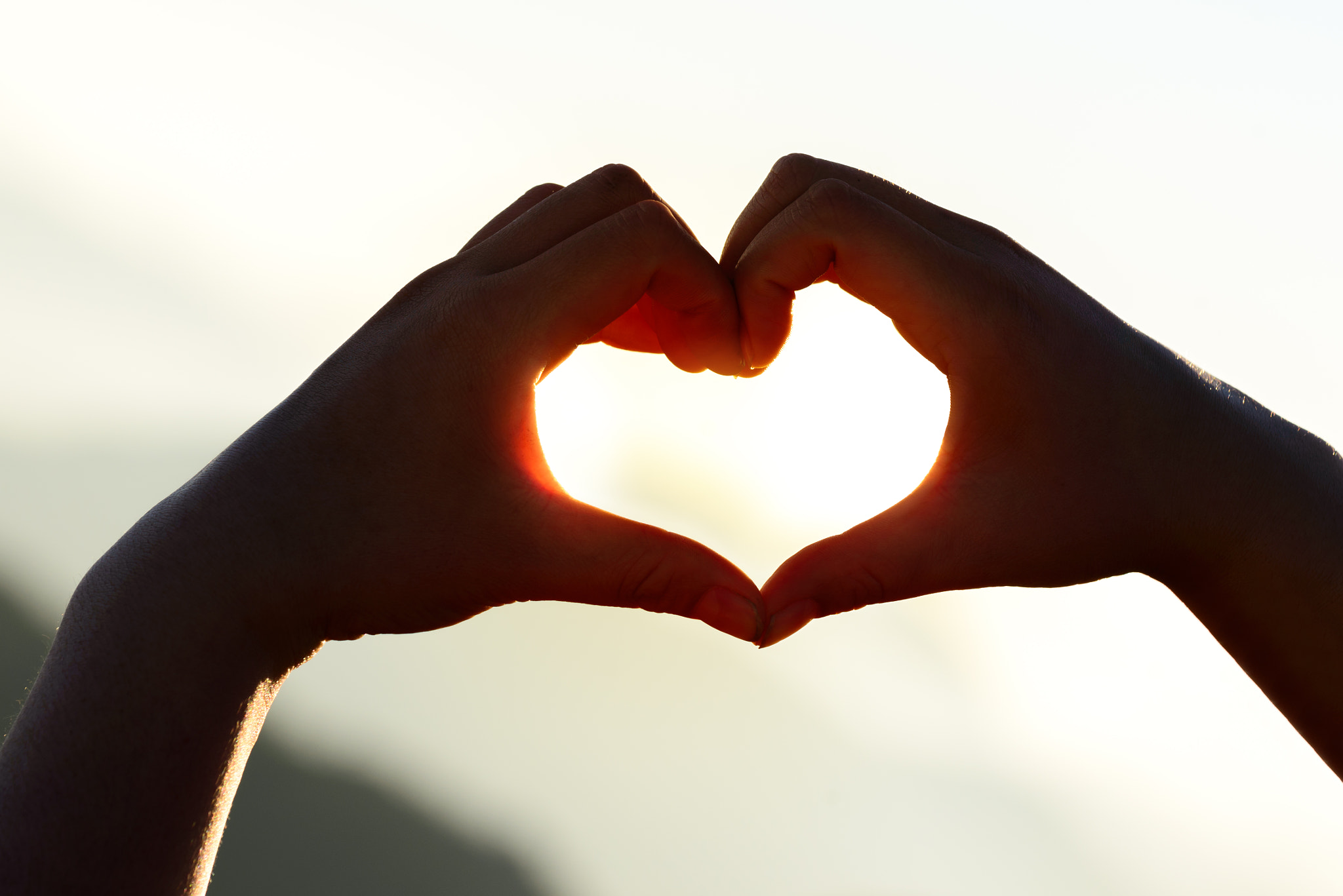 Nikon AF-S Nikkor 70-200mm F4G ED VR sample photo. Hands forming a heart shape at sunset with mountains background. photography