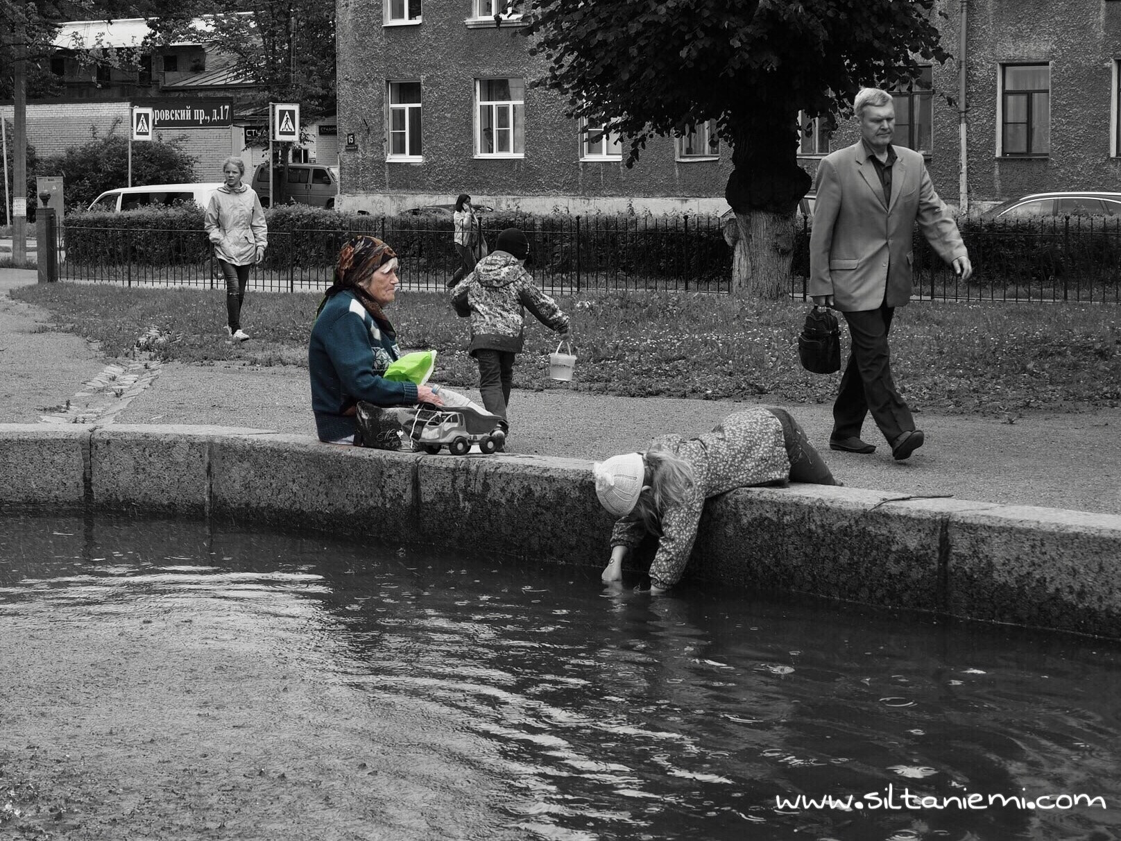 Olympus OM-D E-M10 II sample photo. Old russian woman sitting alone amidst children and passers by in vyborg, russia photography