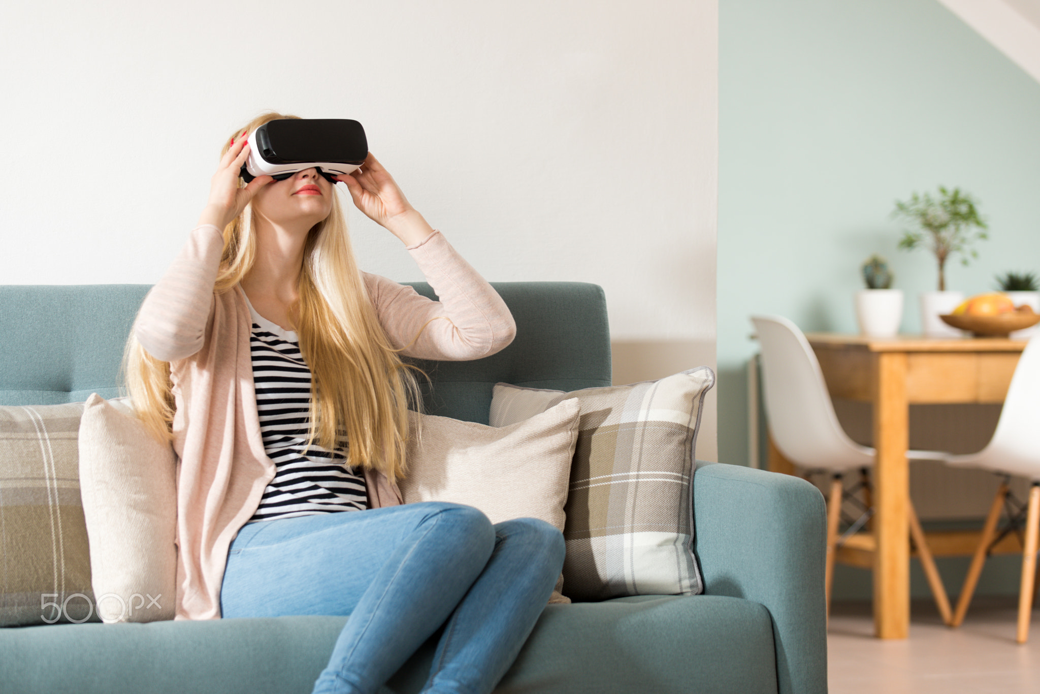 Attractive woman wearing virtual reality glasses lying on a couch. Virtual reality headset....