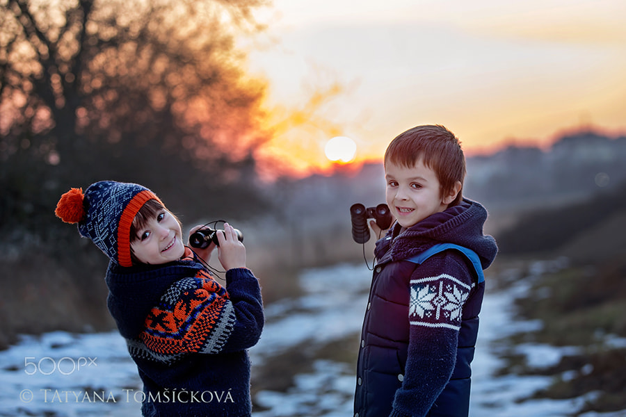 Two little children, boys, exploring nature with binoculars