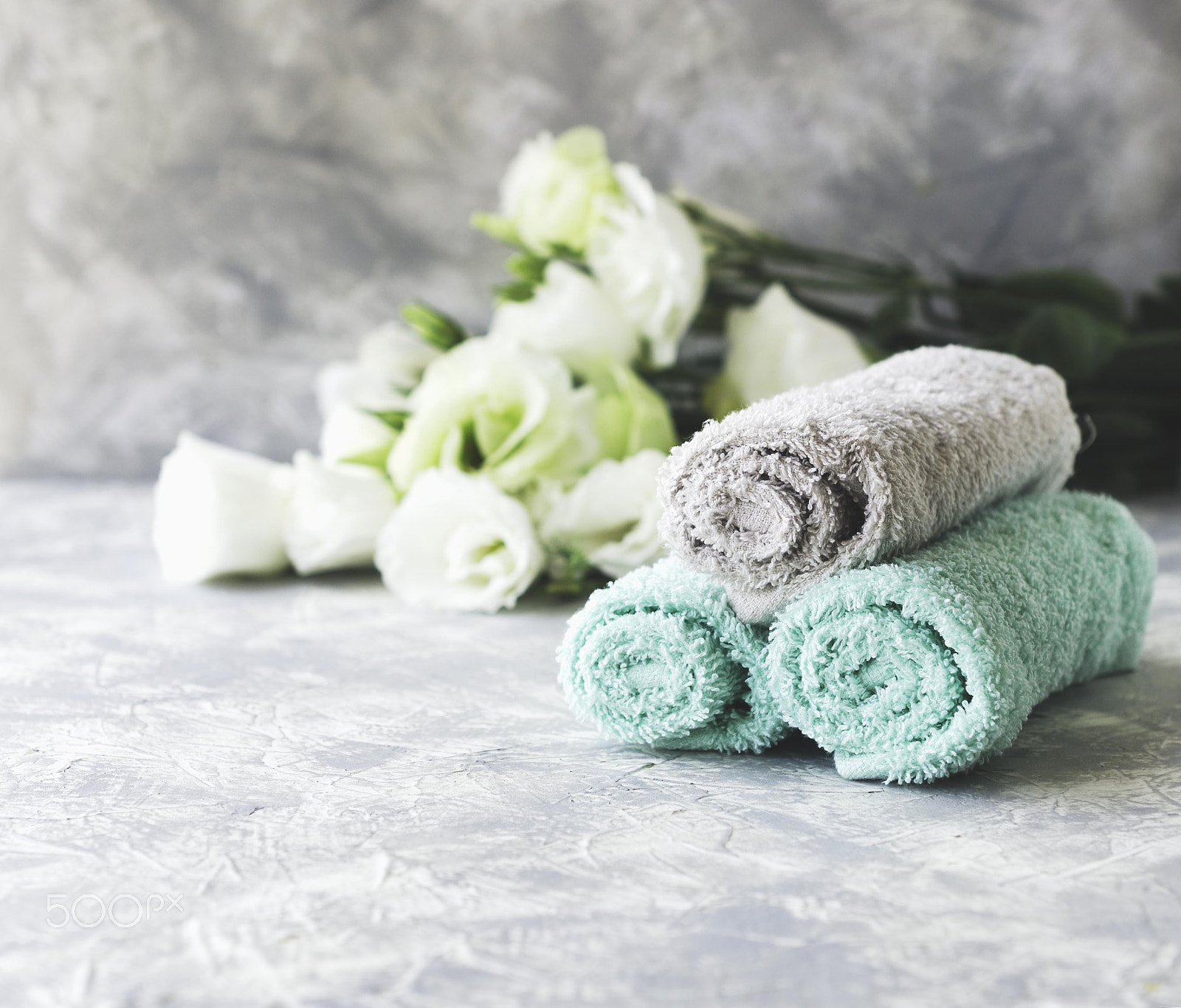 Nikon D7000 sample photo. Stack of towels with flowers for spa space under the text, selective focus photography