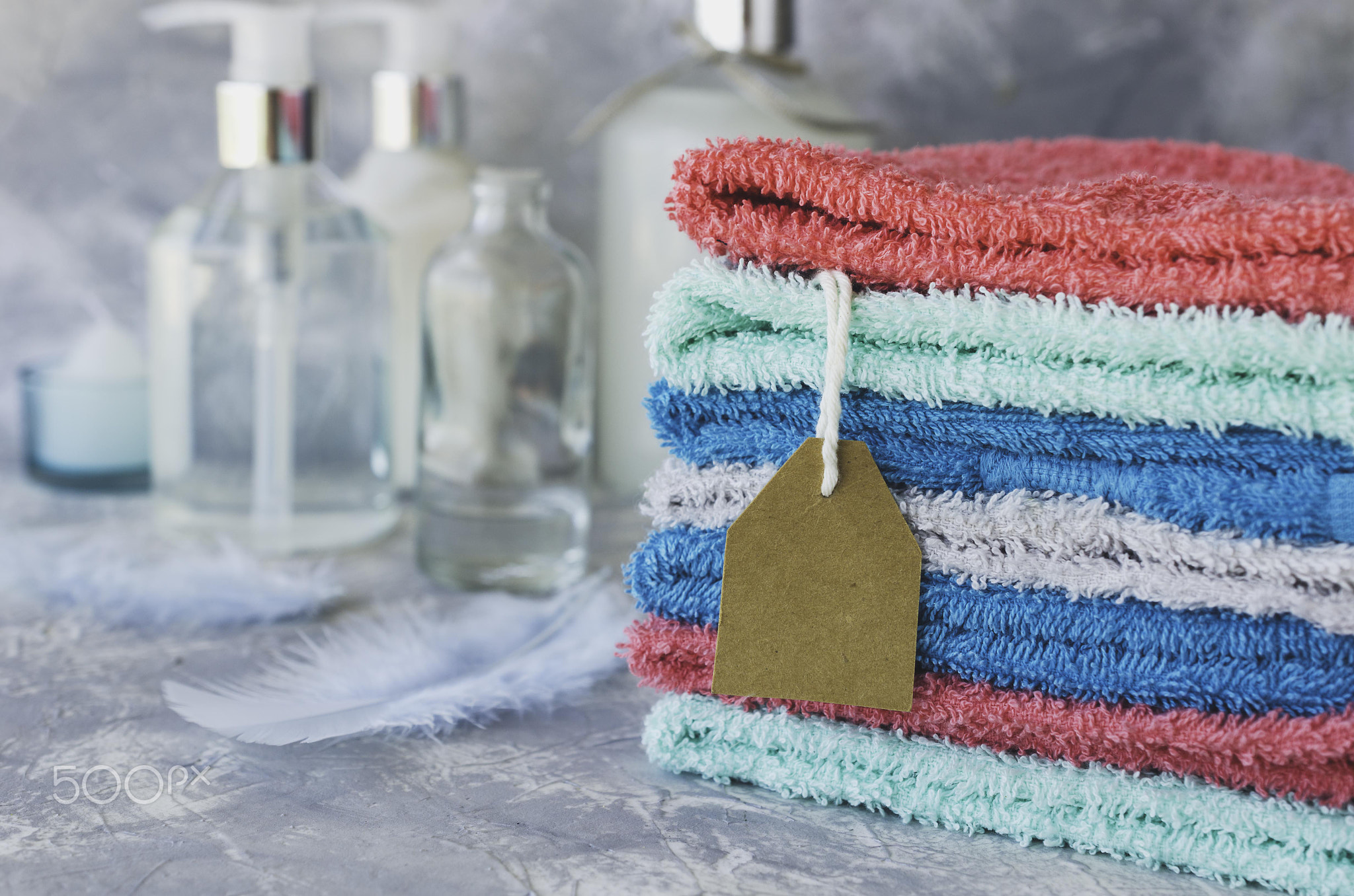 Towel stack with price tag on a white marble background, space for text, selective focus