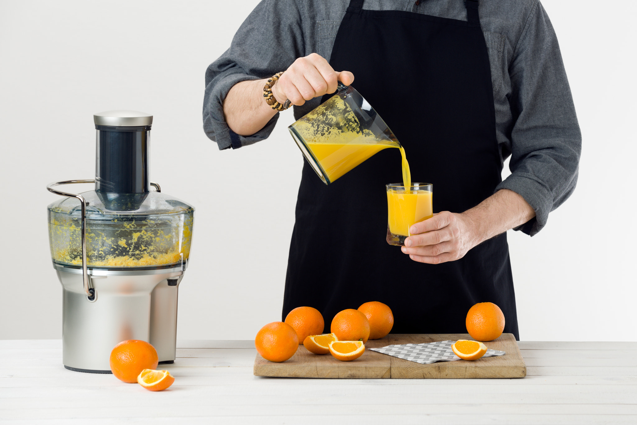 Nikon D810 sample photo. Anonymous man wearing an apron, pouring freshly prepared orange juice into a glass, healthy... photography