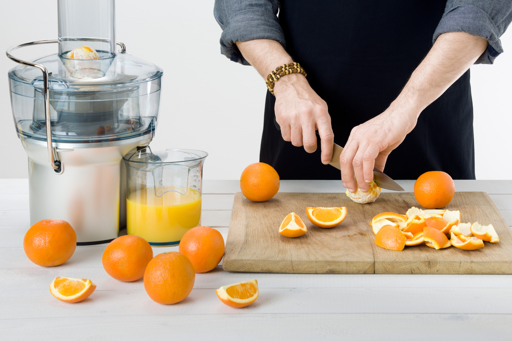 Nikon D810 sample photo. Anonymous man wearing an apron, preparing healthy orange juice, using modern electric juicer,... photography