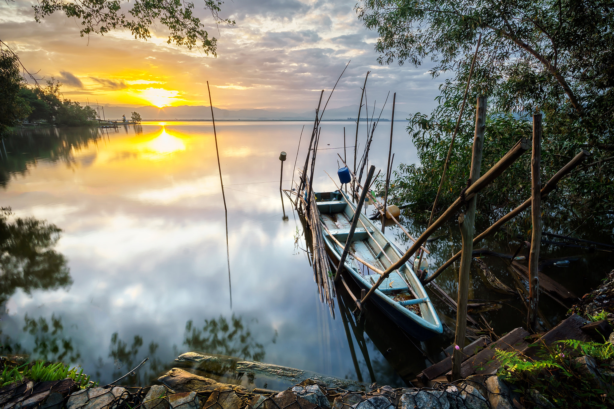 Sony a6000 sample photo. The fisherman boat tied at the lake side with the golden sunrise reflection over the calm water photography