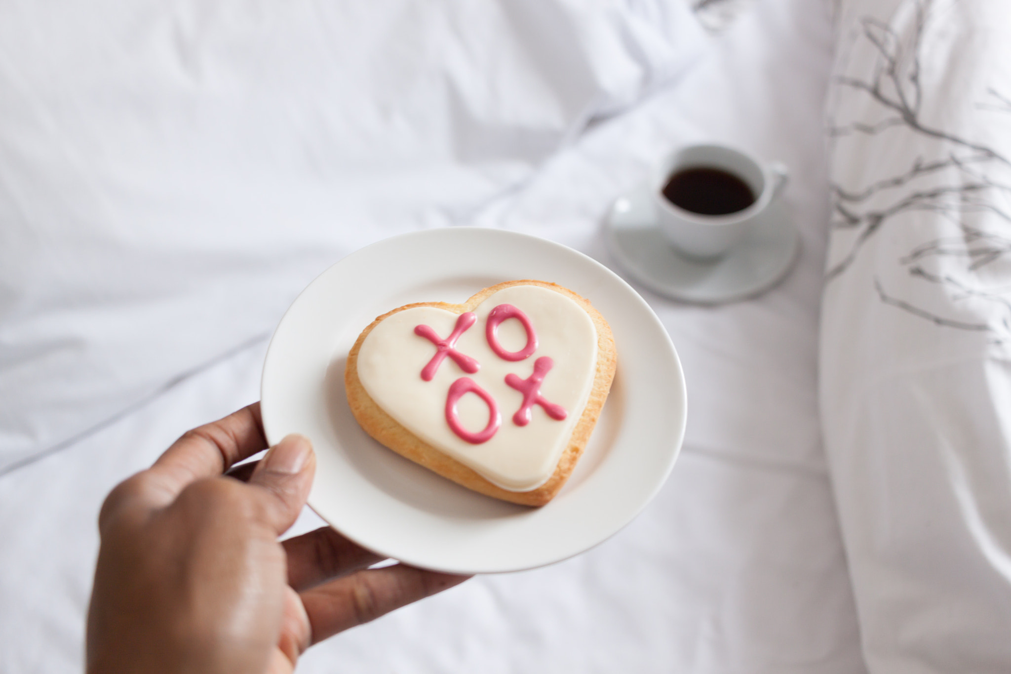 Canon EF-S 24mm F2.8 STM sample photo. Hand giving a heart-shaped cookie on a bed with cup of coffee photography