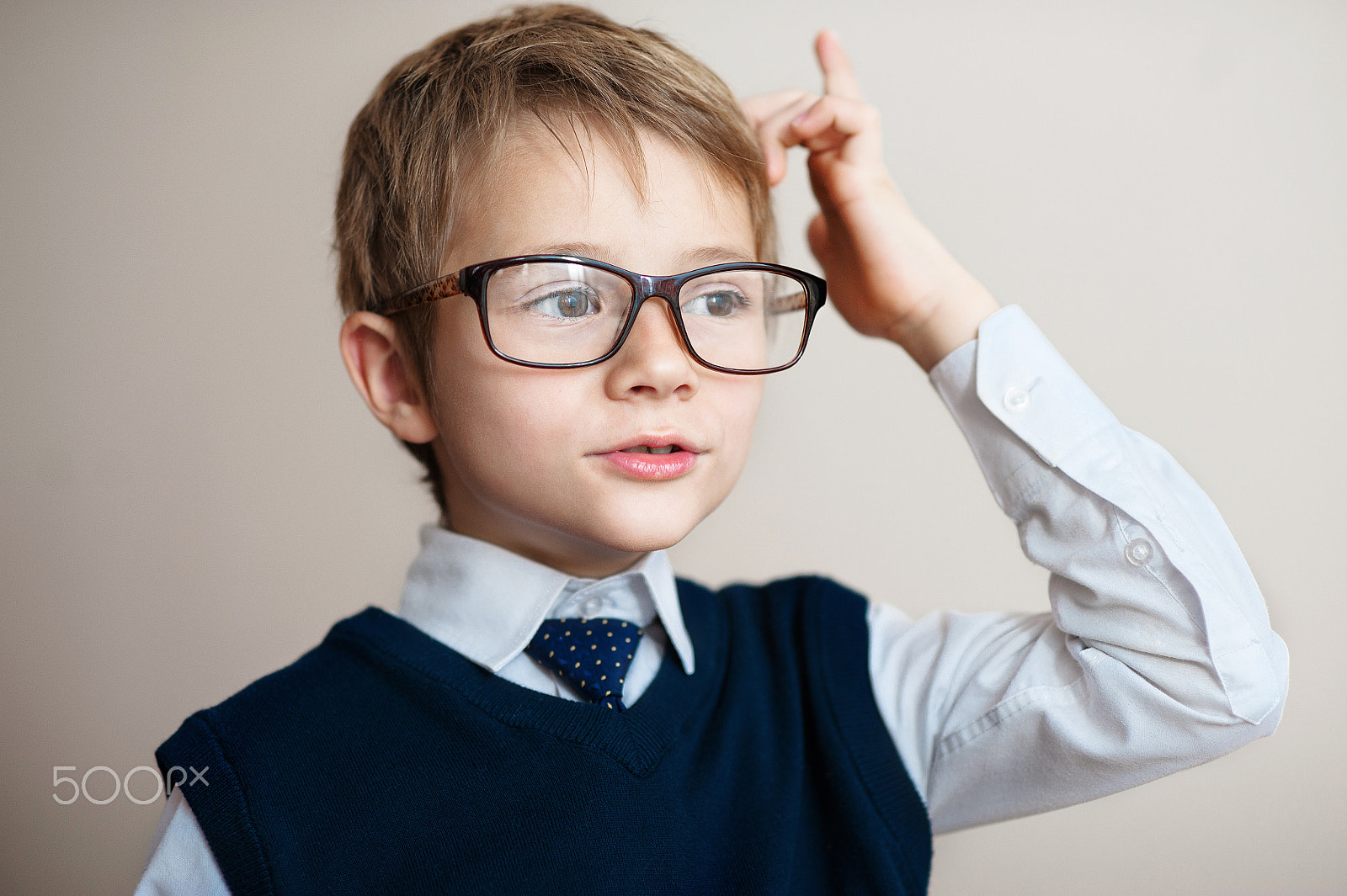 Nikon D700 + Nikon AF Nikkor 85mm F1.8D sample photo. Young boy in big glasses showing finger up over gray background photography