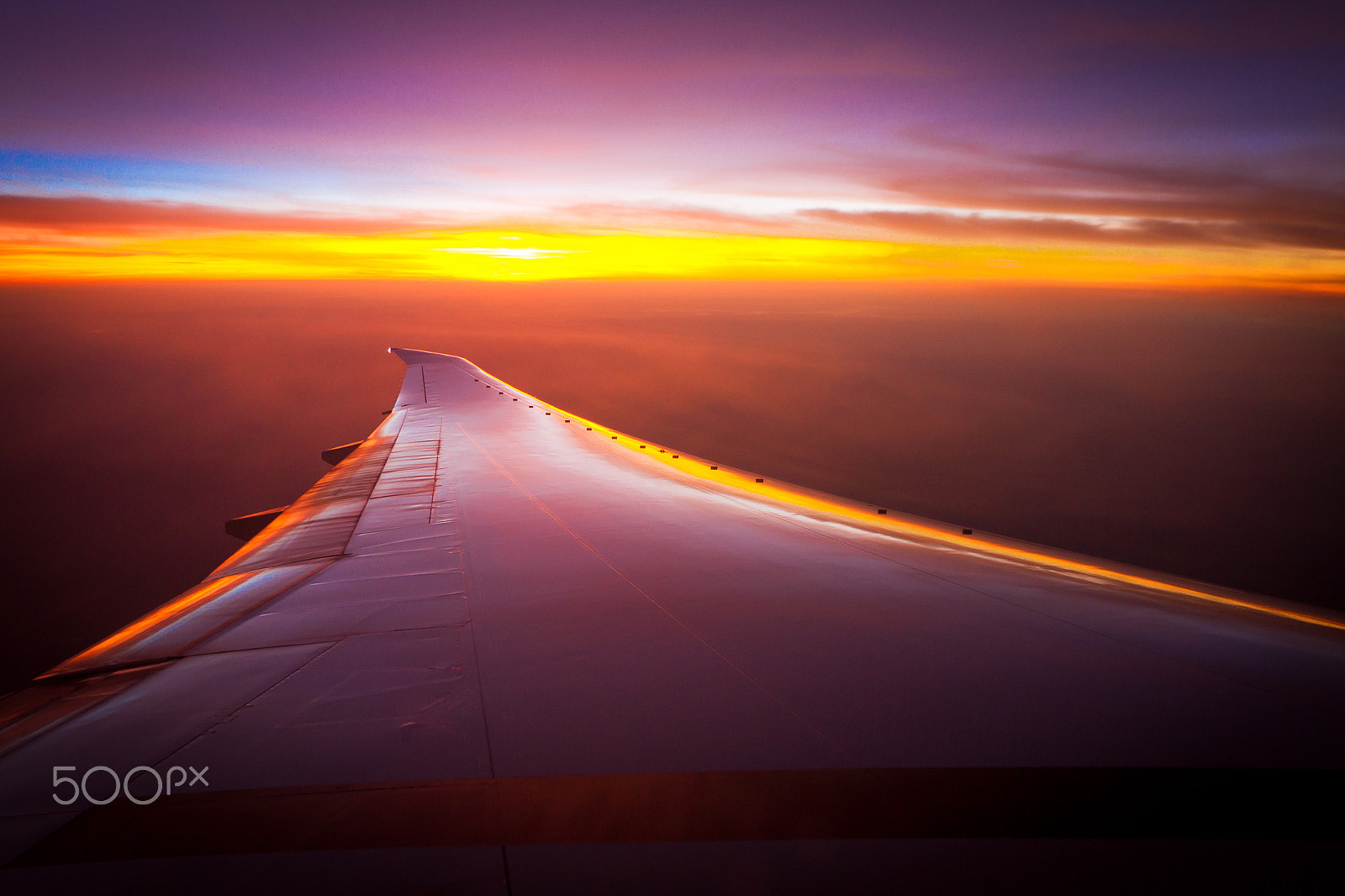 Canon EOS 7D + Canon EF 16-35mm F2.8L II USM sample photo. Plane wing flying through a colorful sunset photography