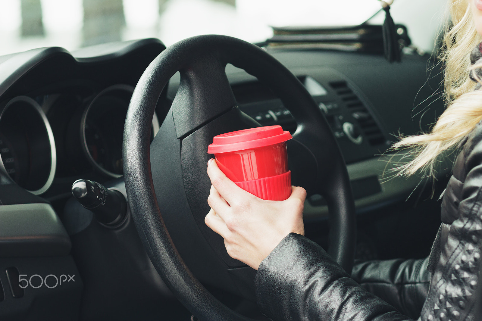 Canon EOS 600D (Rebel EOS T3i / EOS Kiss X5) + Canon EF 85mm F1.8 USM sample photo. Woman with a red cup of hot drink keeps the wheel of a car photography