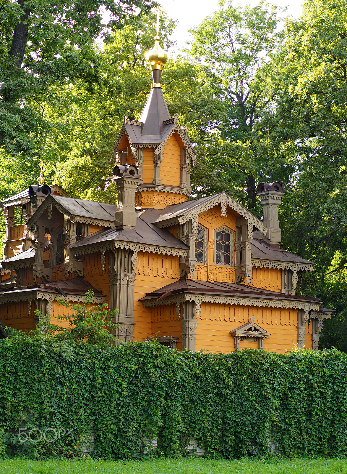 Sony SLT-A65 (SLT-A65V) sample photo. Church of orange color of wood with carved details is behind the green fence surrounded by trees photography