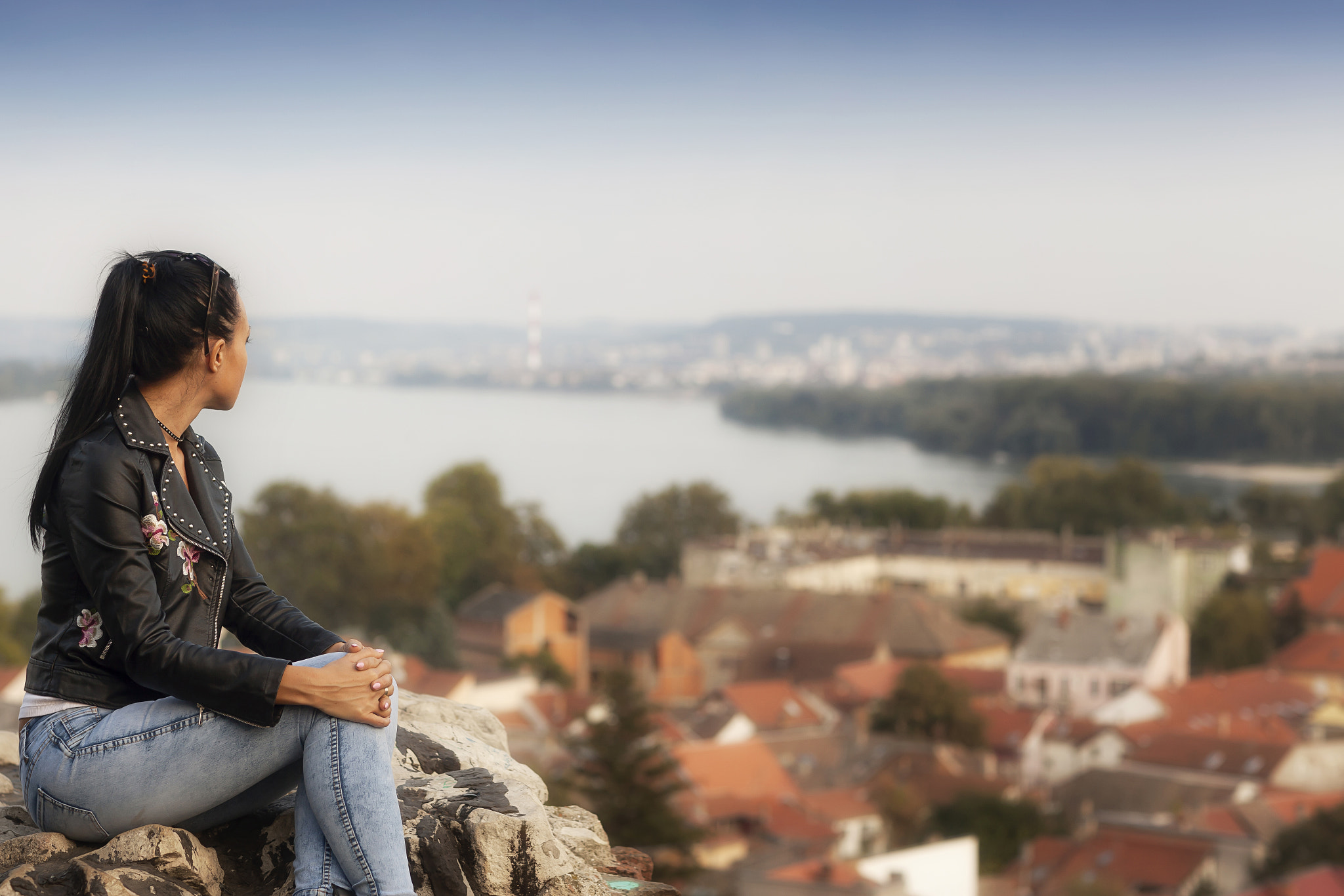 Canon EF 85mm F1.2L II USM sample photo. Traveller girl sits on a rock and looking at the beautiful panorama of the city, river photography
