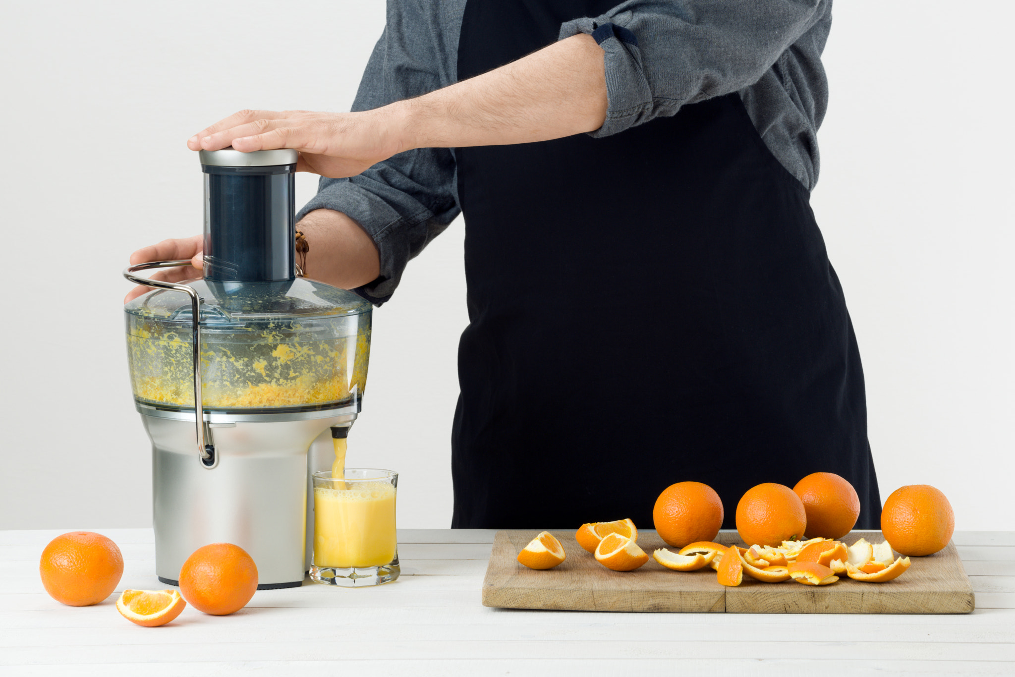 Nikon D810 sample photo. Anonymous man wearing an apron, preparing healthy orange juice, using modern electric juicer,... photography