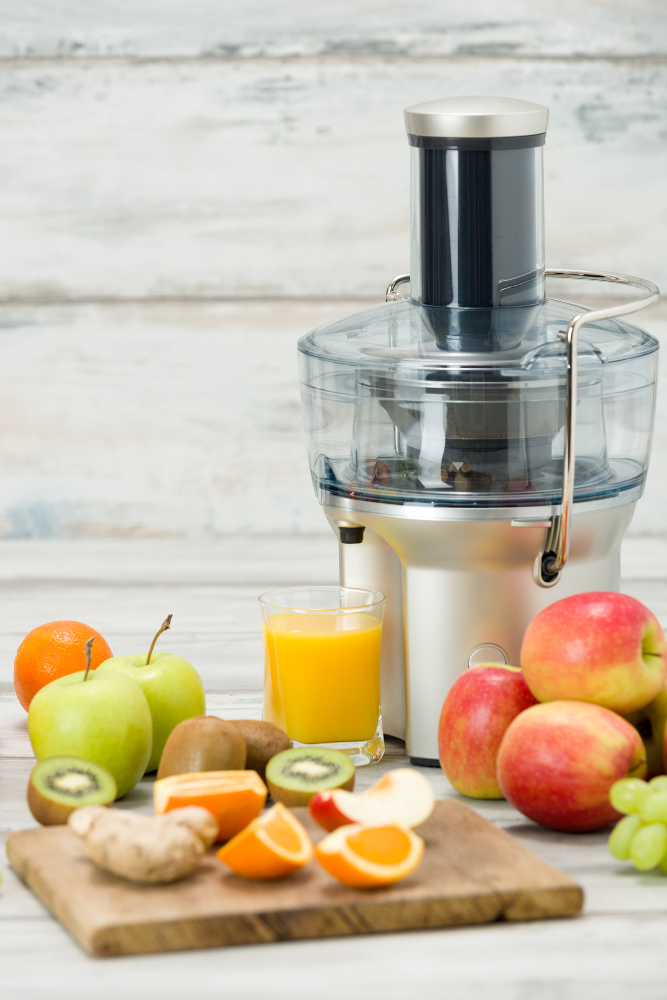 Modern electric juicer, various fruit and glass of freshly made juice, healthy lifestyle concept