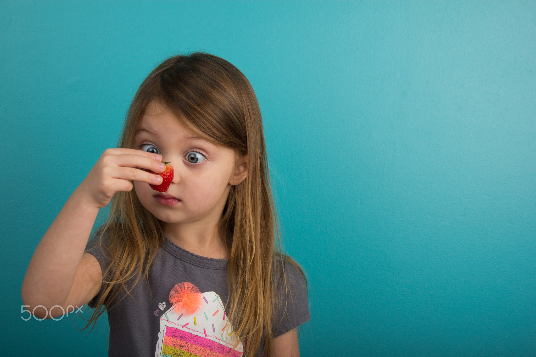 Little girl looking at a strawberry