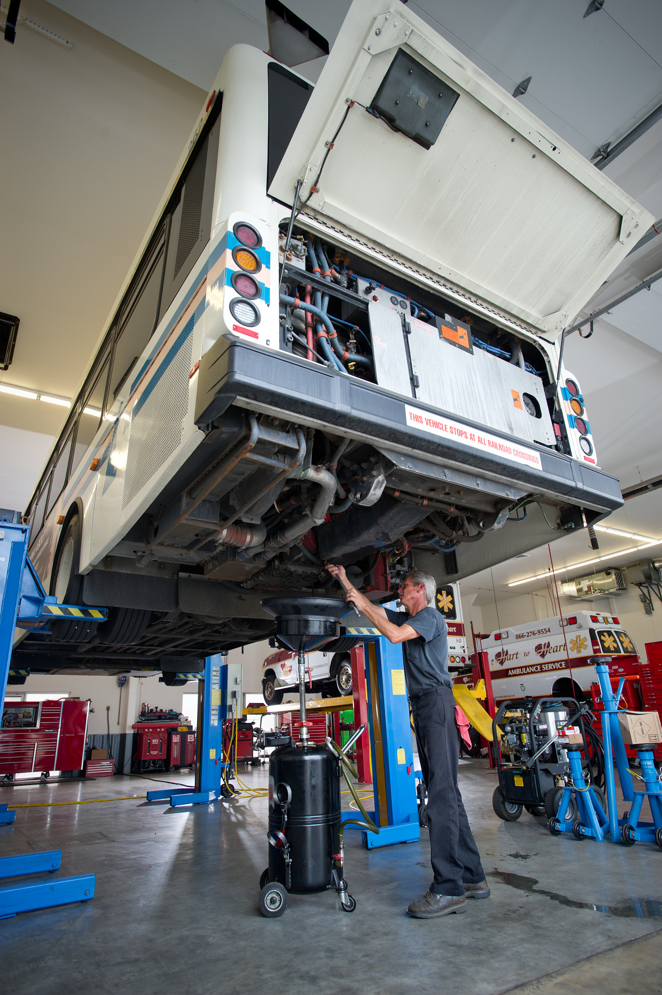 Nikon AF-S Nikkor 17-35mm F2.8D ED-IF sample photo. Man working on a bus on a lift in an auto garage of an ambulatory care unit photography