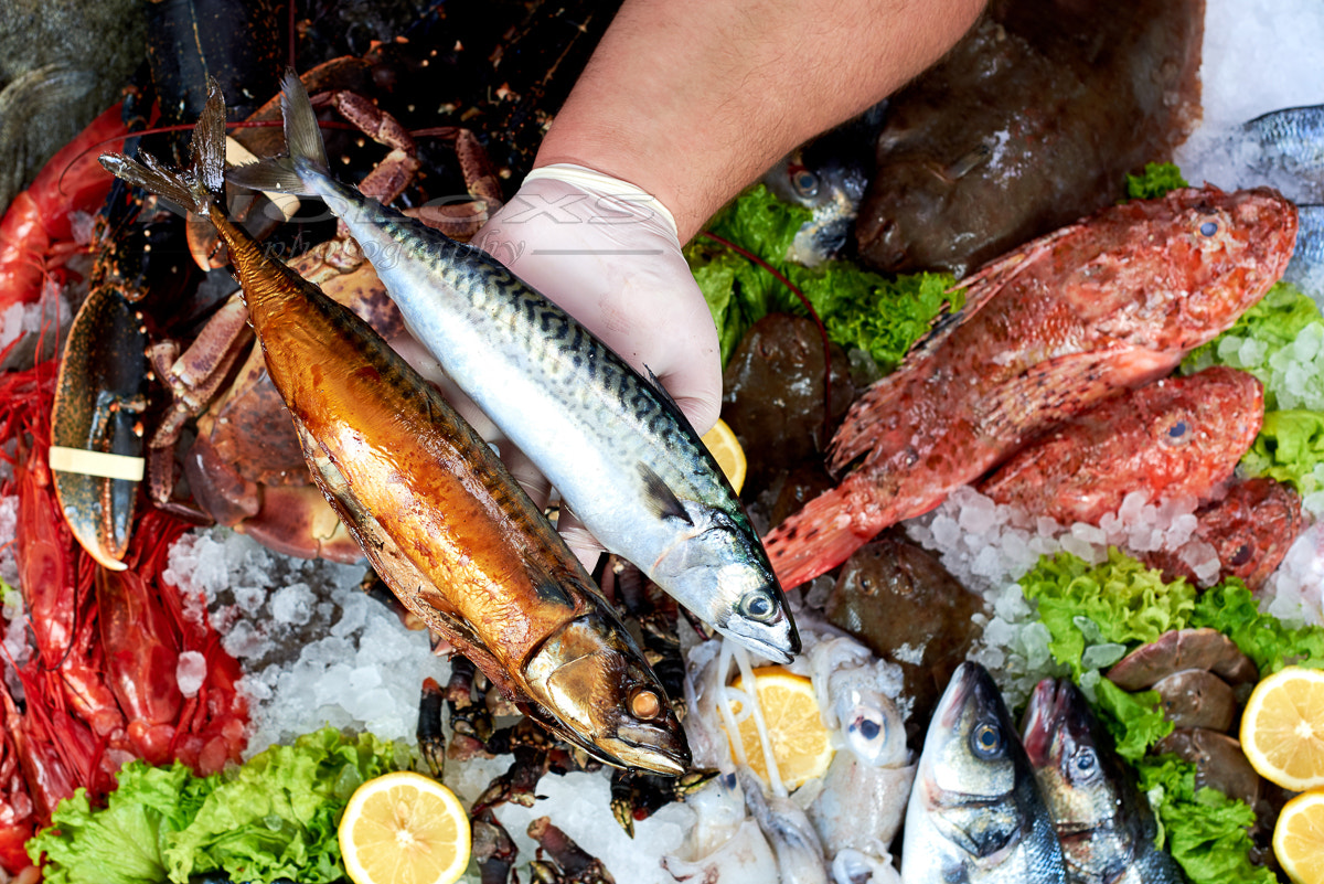 Seller presenting a fresh and smoked mackerel fish in fish store