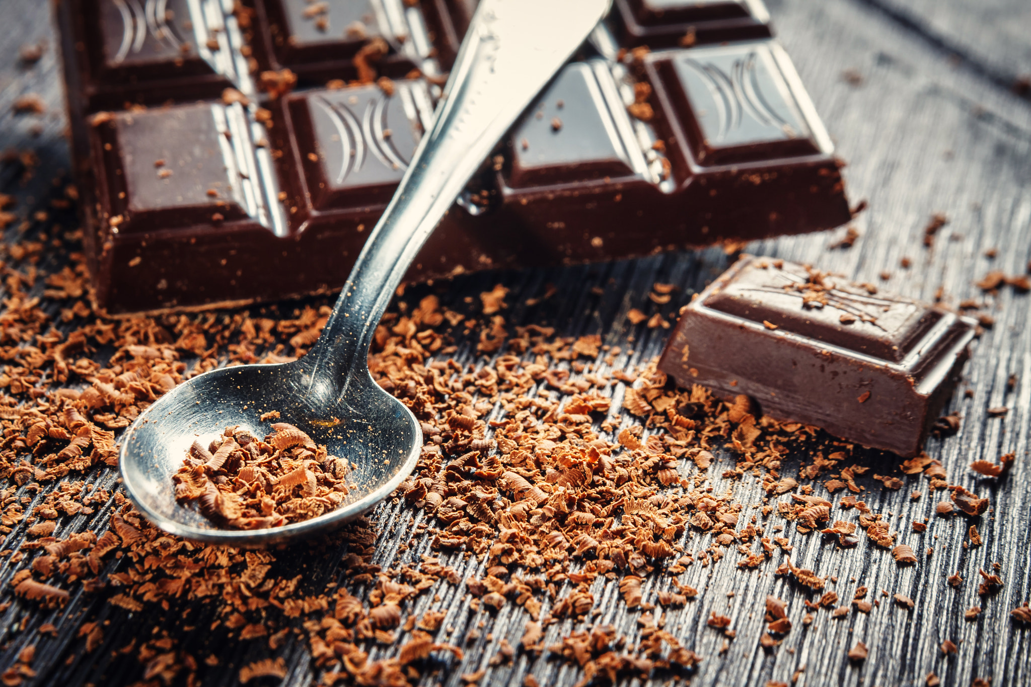 Close up of dark chocolate and spoon on dark wooden background