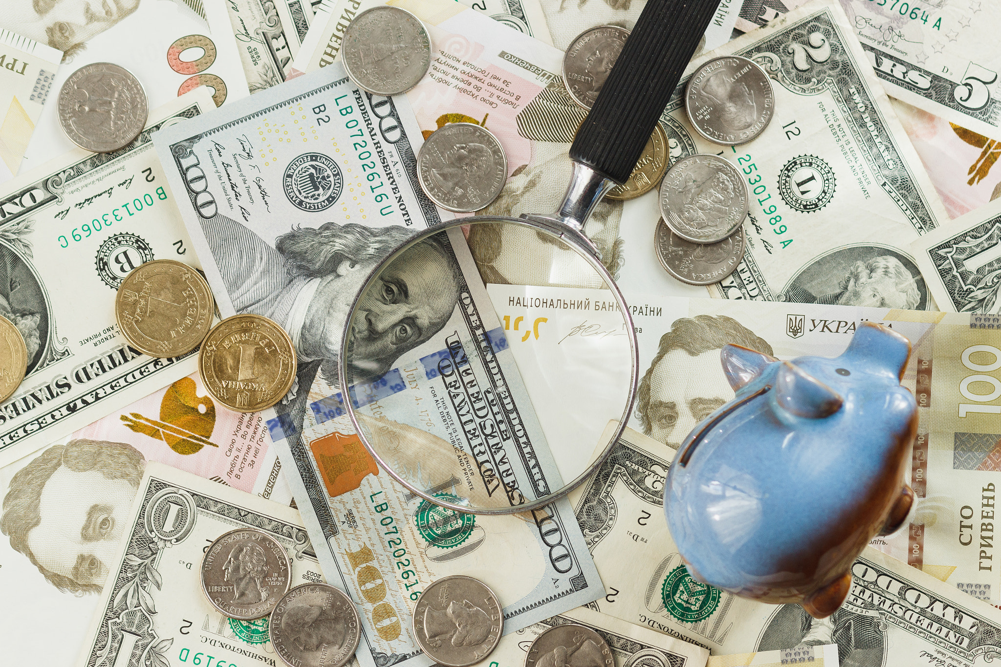 Canon EOS 600D (Rebel EOS T3i / EOS Kiss X5) + Canon EF 85mm F1.8 USM sample photo. Ukrainian hryvnia and american's dollars with a piggy bank and magnifying glass photography