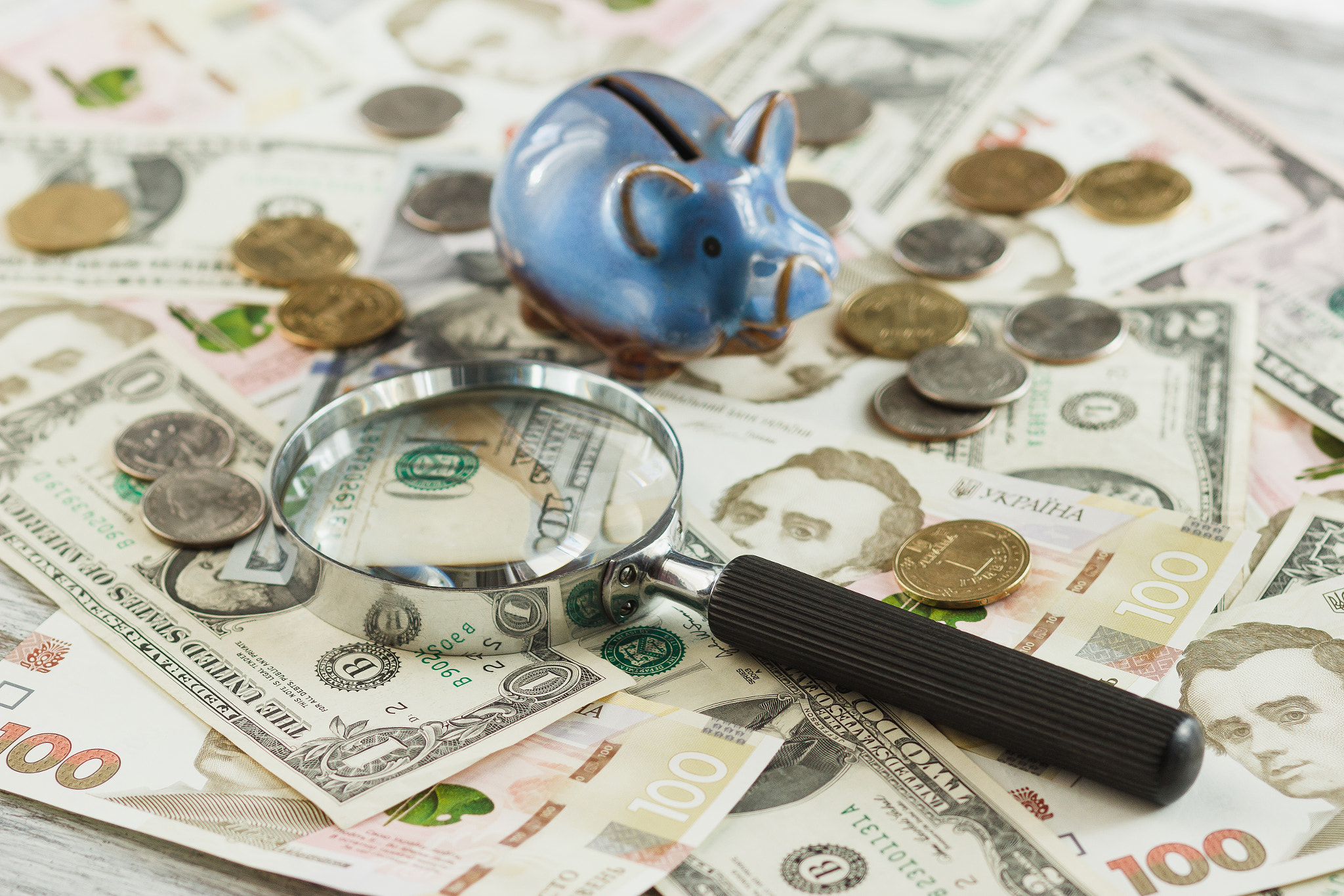 Canon EOS 600D (Rebel EOS T3i / EOS Kiss X5) + Canon EF 85mm F1.8 USM sample photo. Ukrainian hryvnia and american's dollars with a piggy bank and magnifying glass photography