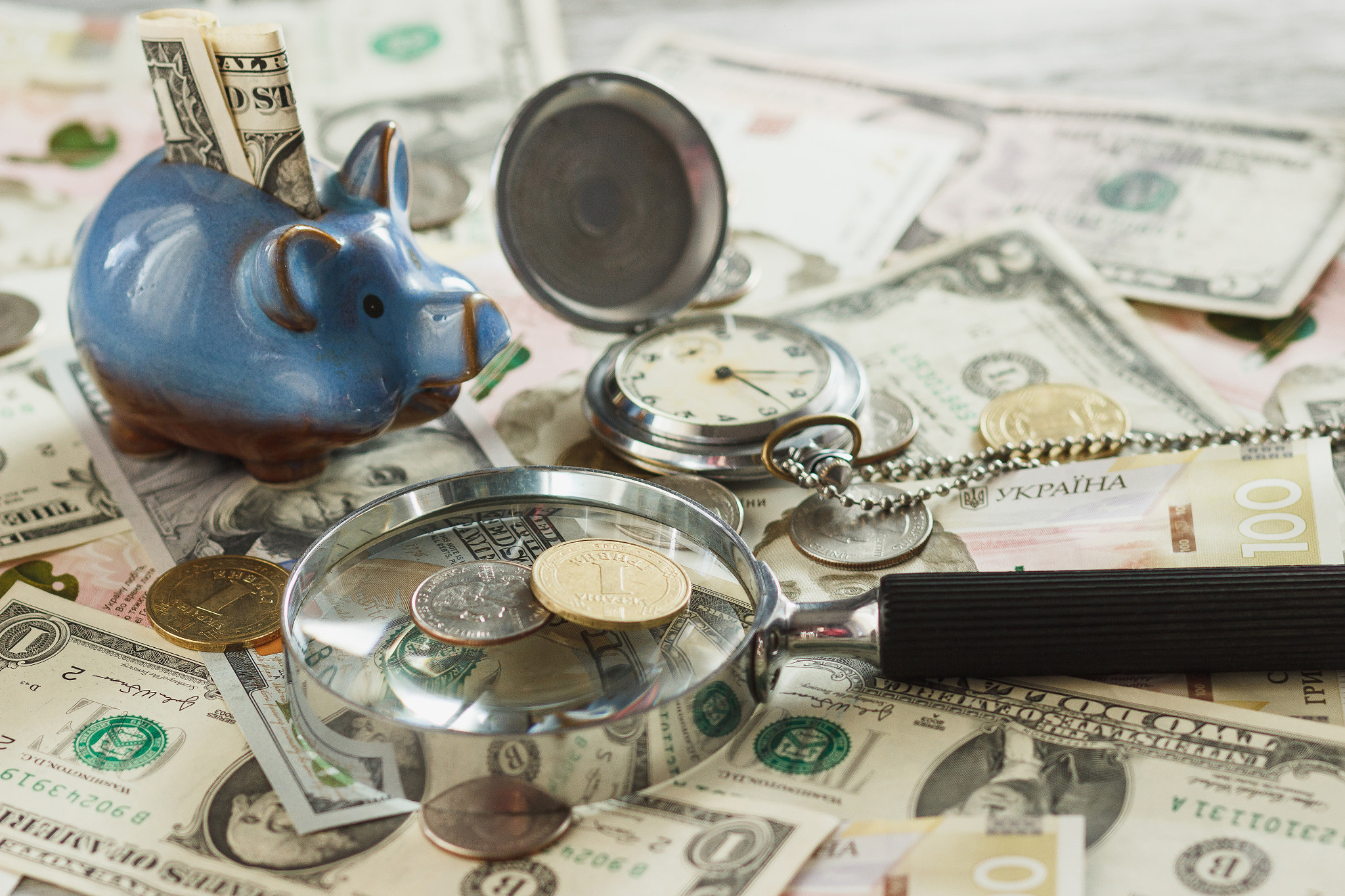 Canon EOS 600D (Rebel EOS T3i / EOS Kiss X5) + Canon EF 85mm F1.8 USM sample photo. Coins and banknotes with a piggy bank, clock and magnifying glass photography