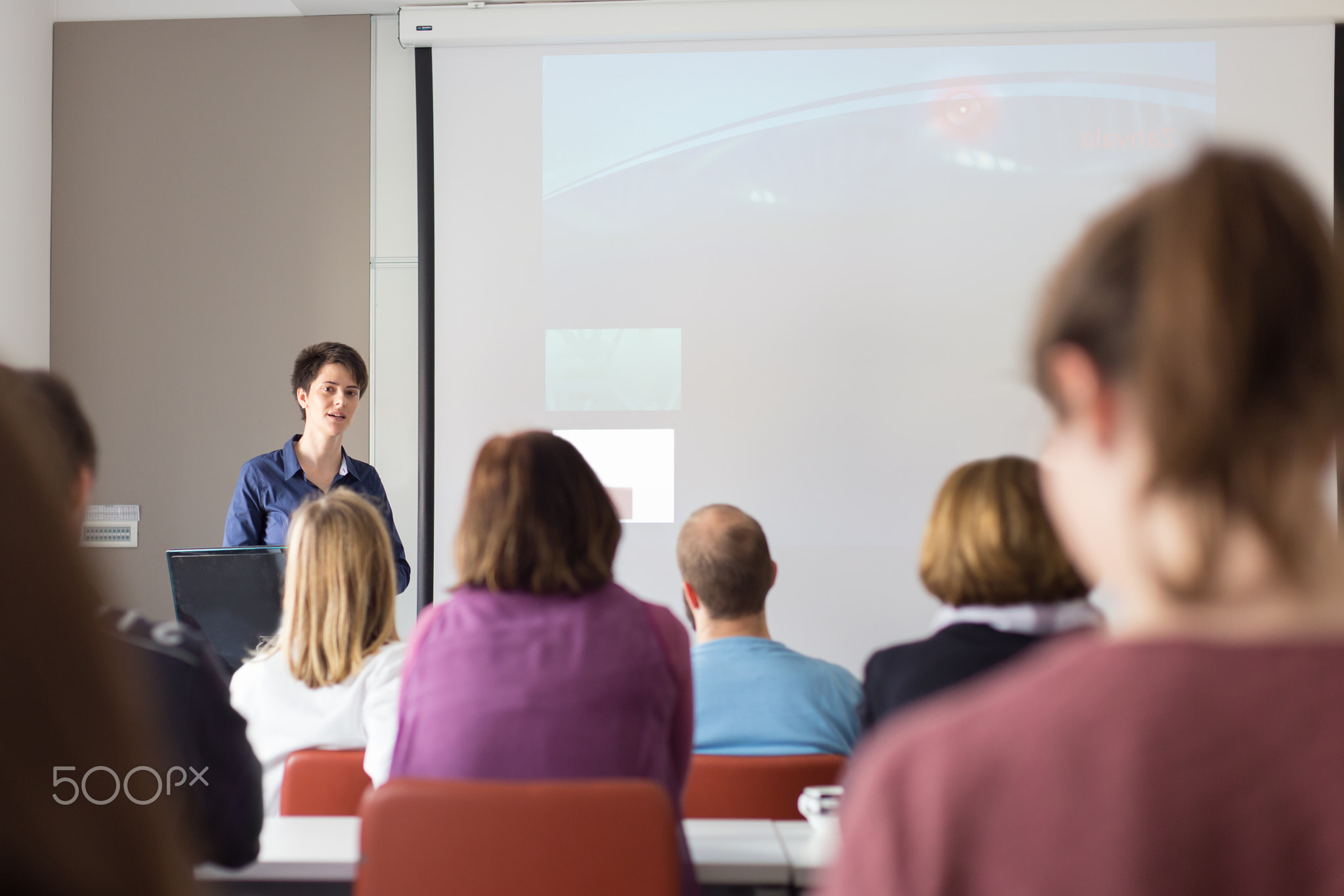Woman giving presentation in lecture hall at university.