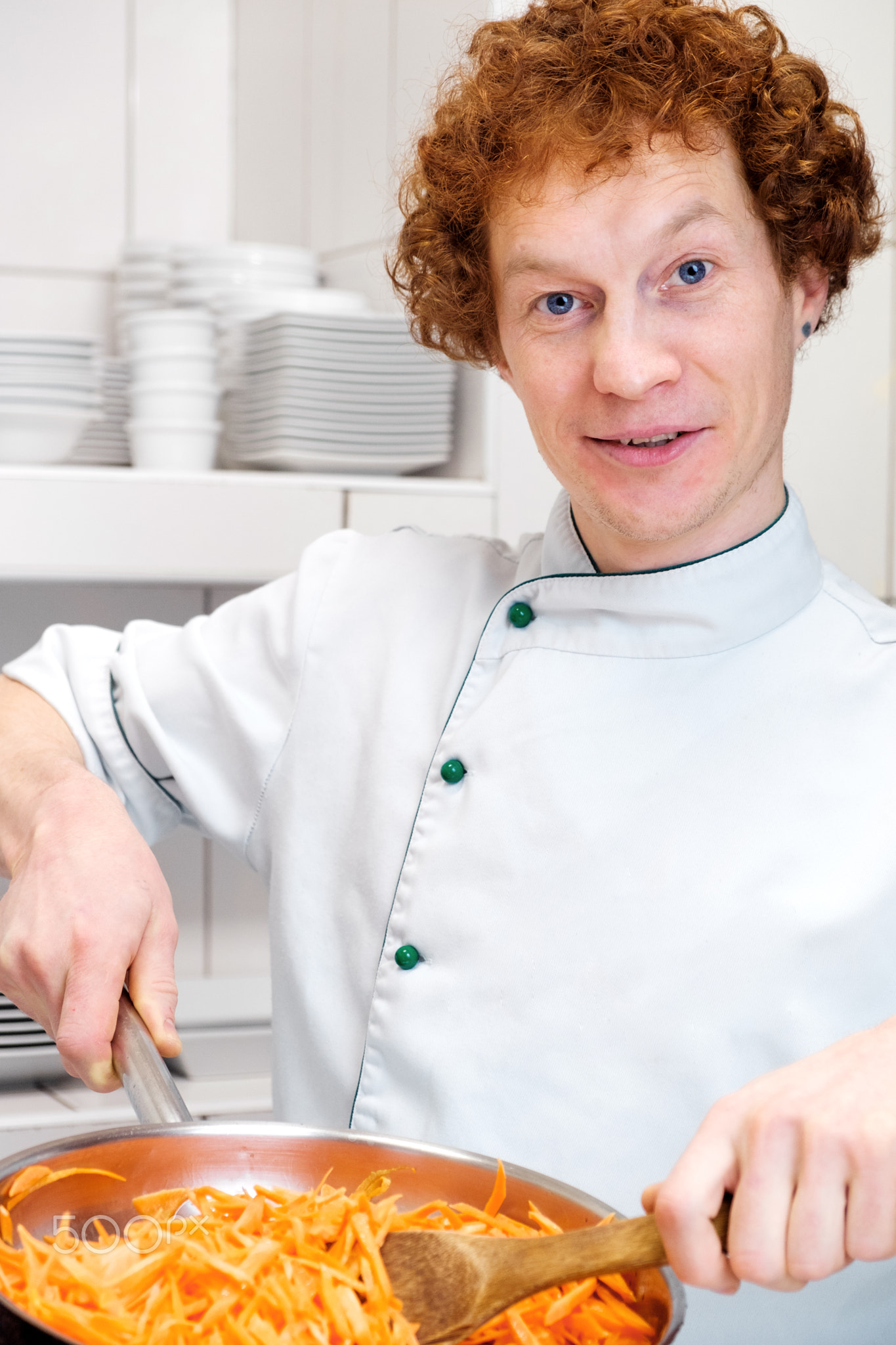 Male chef with red hair in the kitchen. Prepares stewed carrots
