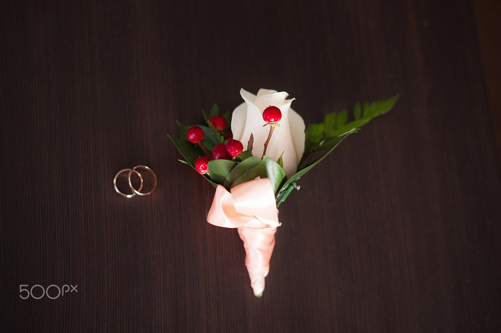 Nikon D700 + Nikon AF-S Nikkor 50mm F1.4G sample photo. Wedding rings on a wooden table with the boutonniere in a vintage style photography