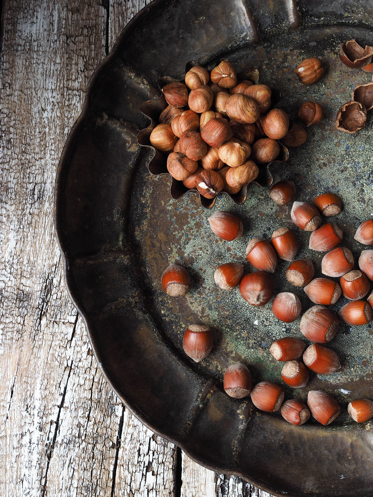 Olympus OM-D E-M10 + Sigma 19mm F2.8 DN Art sample photo. Hazelnuts scattered on an old metal platter and to photography