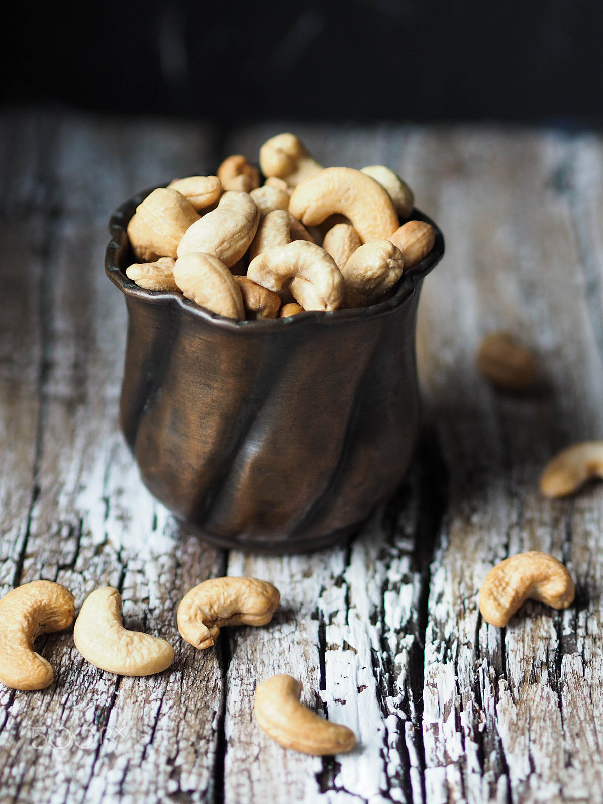 Olympus OM-D E-M10 + Olympus M.Zuiko Digital 45mm F1.8 sample photo. Copper cup full of cashew nuts on an old wooden ba photography