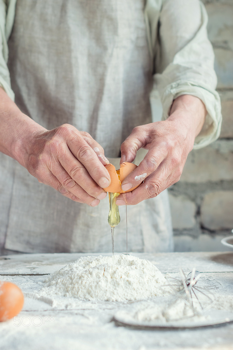 Nikon D3200 + Nikon AF-S Nikkor 50mm F1.4G sample photo. A baker kneads dough. the process of breaking eggs photography